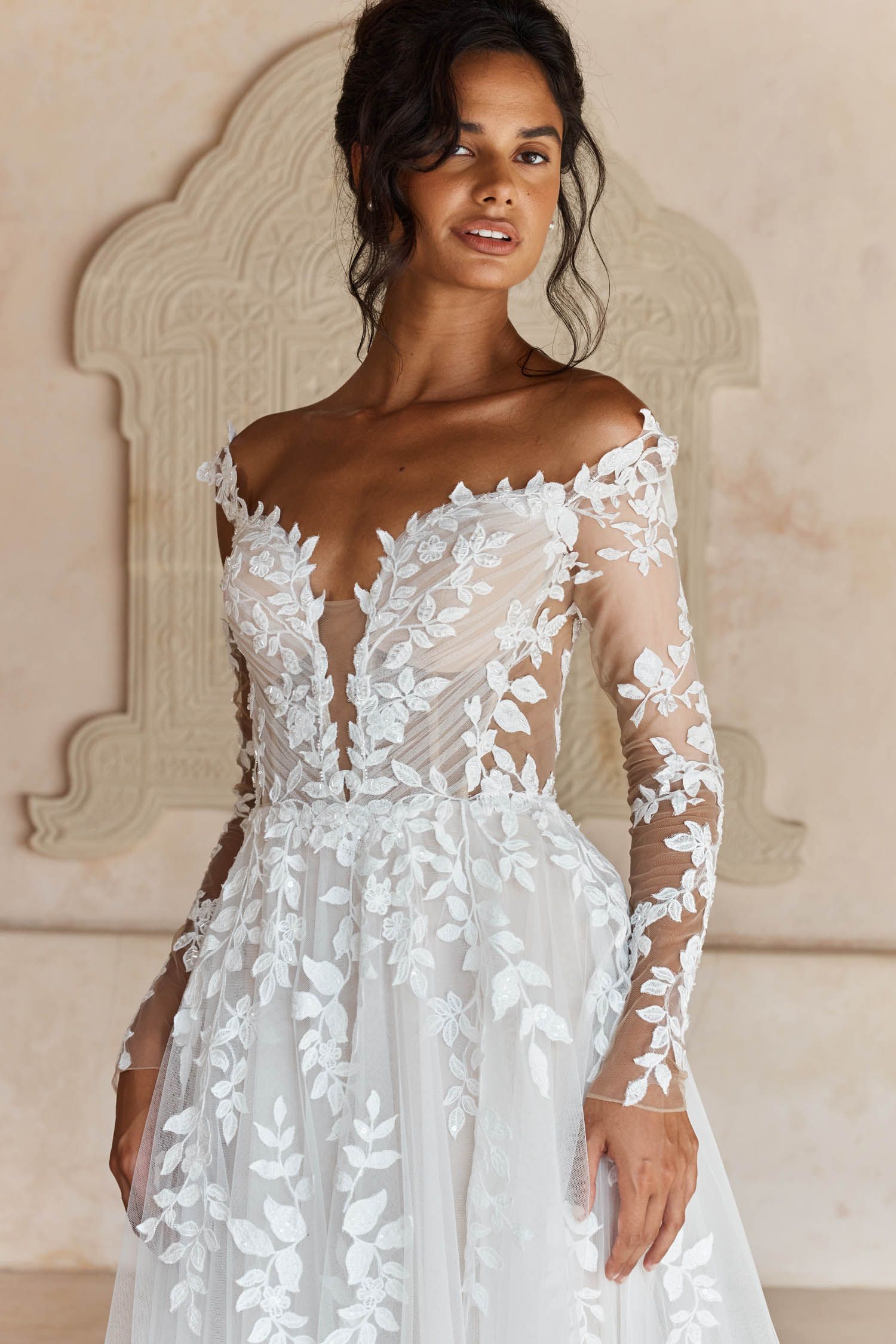 Eine Frau in einem Brautkleid steht an einem steinigen Strand.