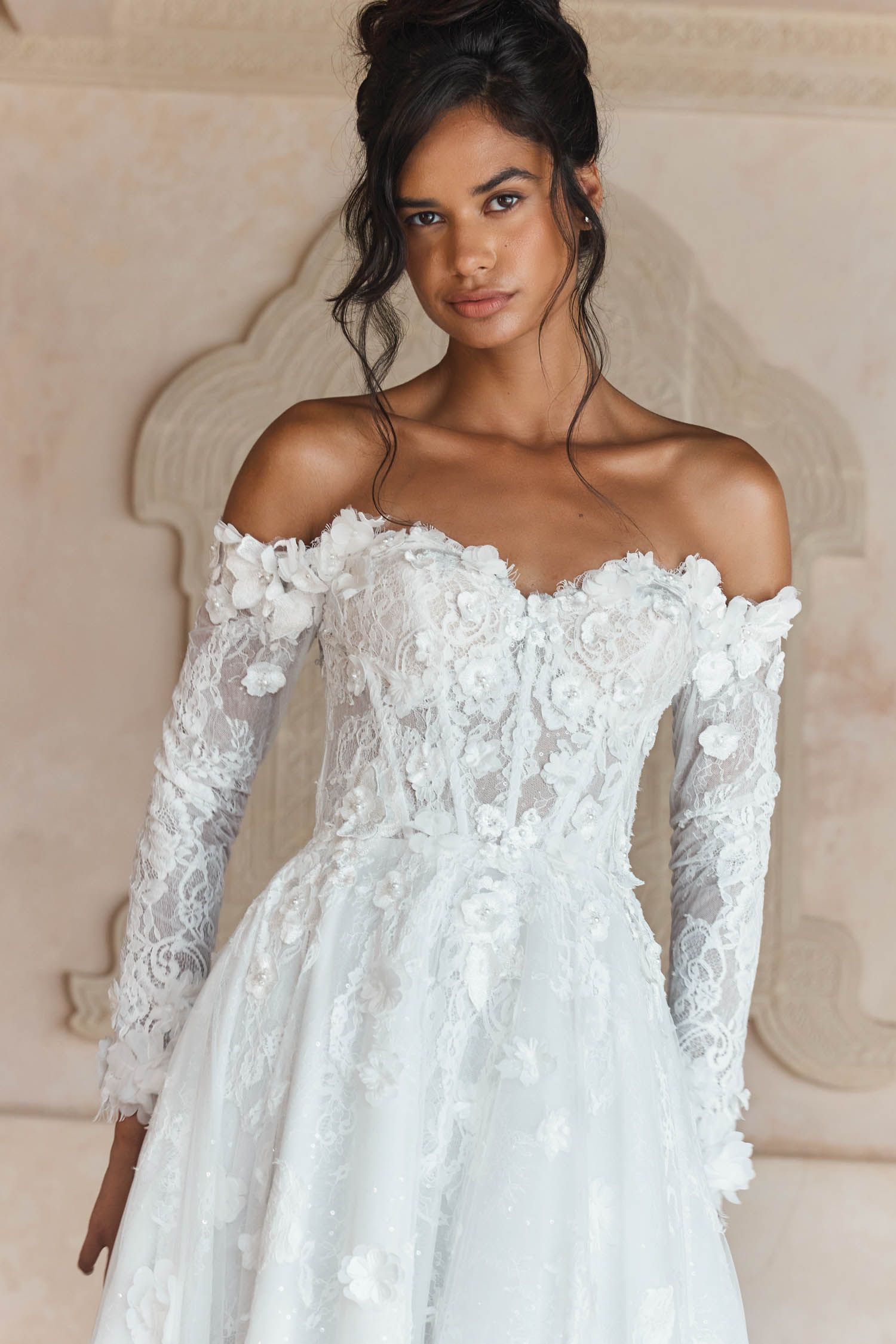 Eine Frau in einem Brautkleid steht an einem steinigen Strand.