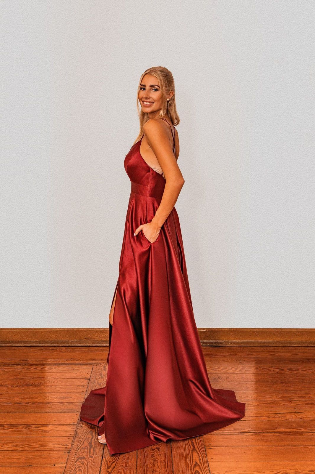 Eine Frau in einem roten Satinkleid steht auf einem Holzboden.