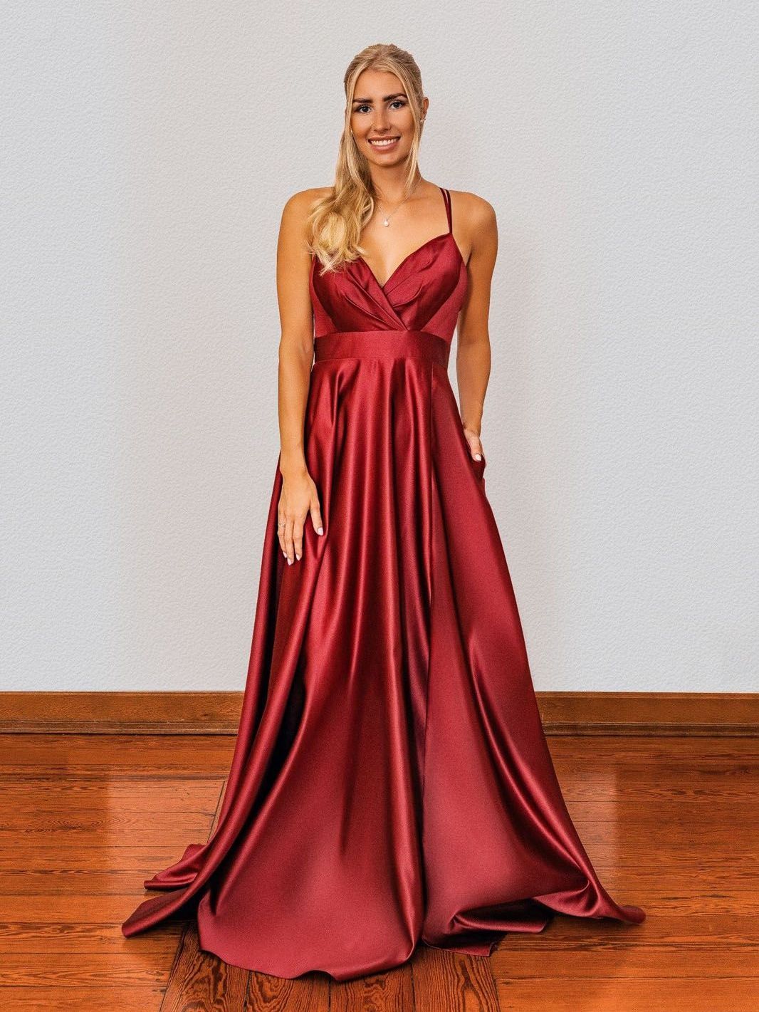 Eine Frau in einem langen roten Kleid steht auf einem Holzboden.