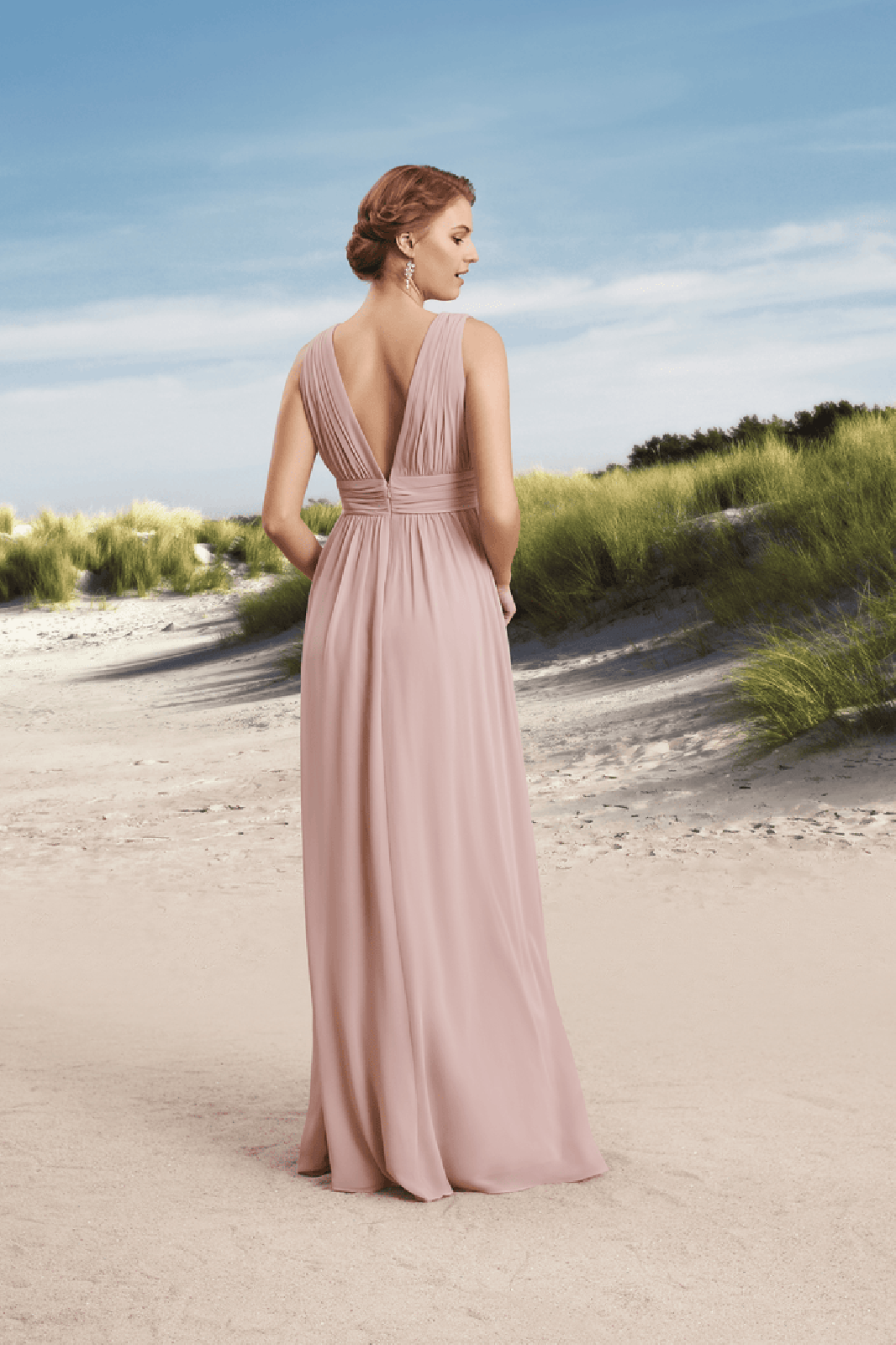 Zu sehen ist der Rücken einer Frau in einem orangefarbenen Kleid.