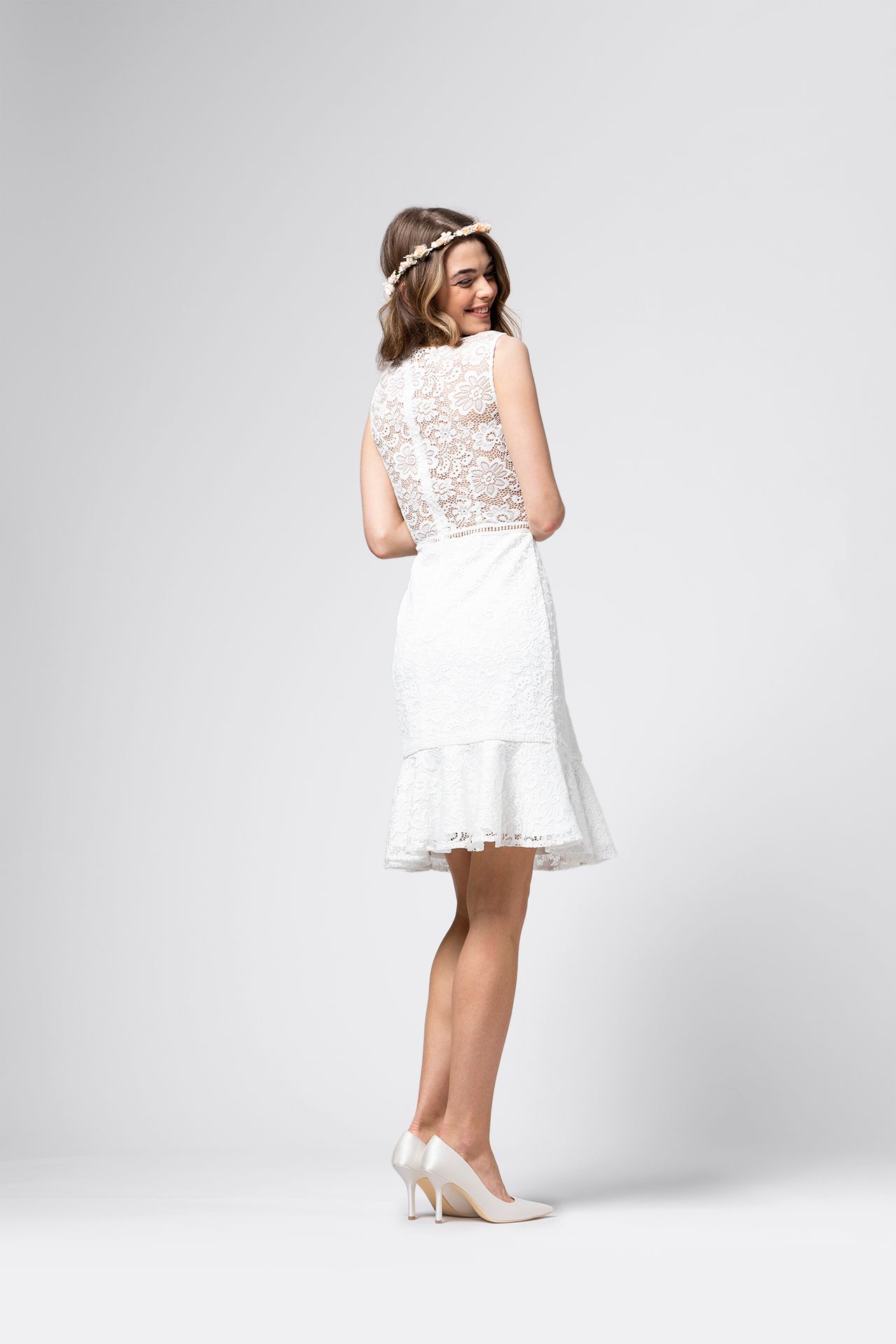 Der Rücken einer Frau, die ein weißes Spitzenkleid und High Heels trägt.