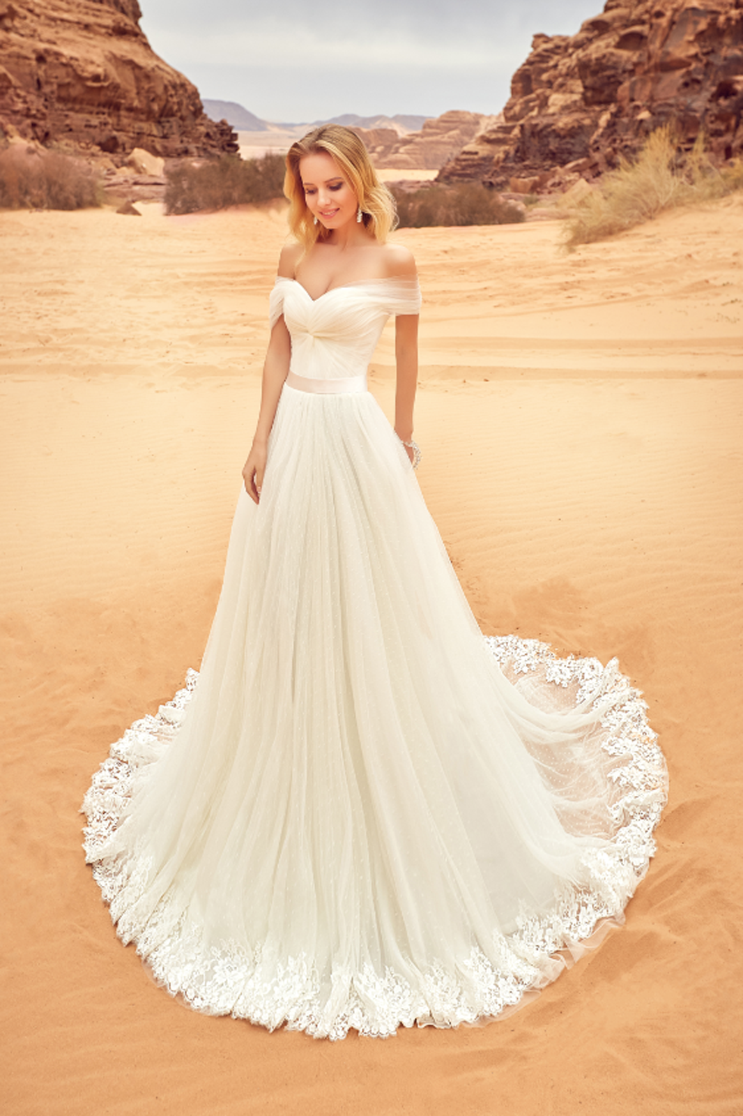 Eine Frau in einem weißen Brautkleid steht vor lila Blumen.
