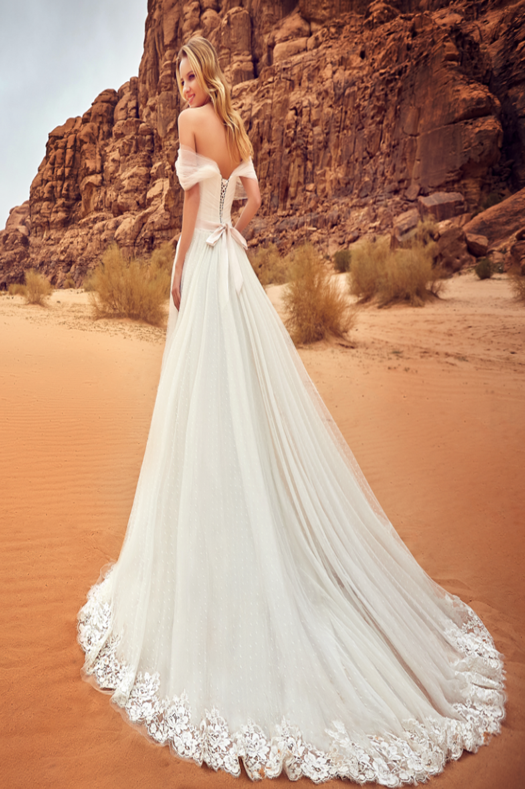 Eine Frau in einem Brautkleid steht auf einer Treppe vor einem Gebäude.