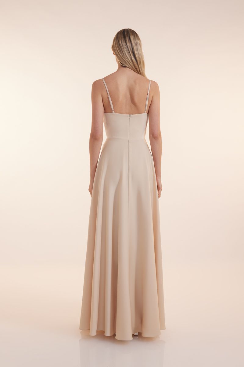 Eine Frau in einem grünen Kleid steht vor einer Holztür.