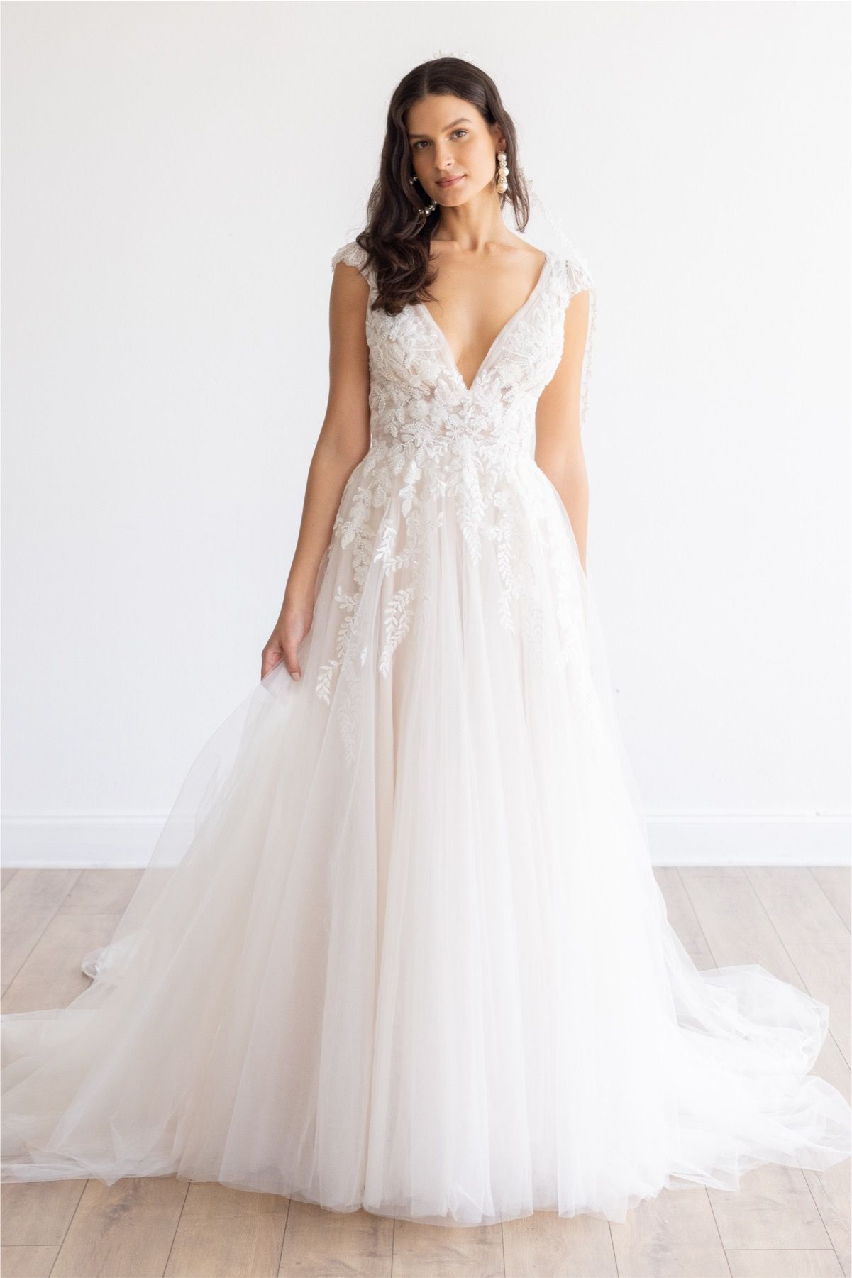 Eine Frau in einem Brautkleid steht an einem steinigen Strand.