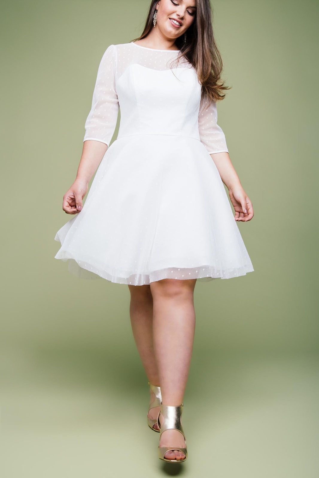 Eine Frau mit Übergröße trägt ein weißes Kleid und goldene Schuhe.