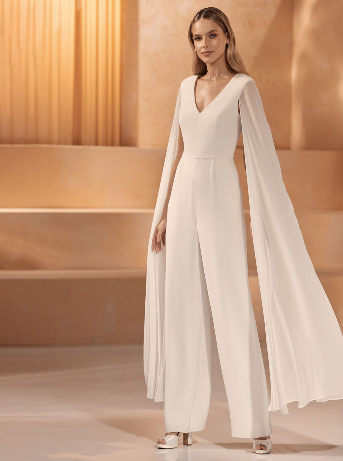 Eine Frau in einem weißen Brautkleid steht vor einem Gebäude.