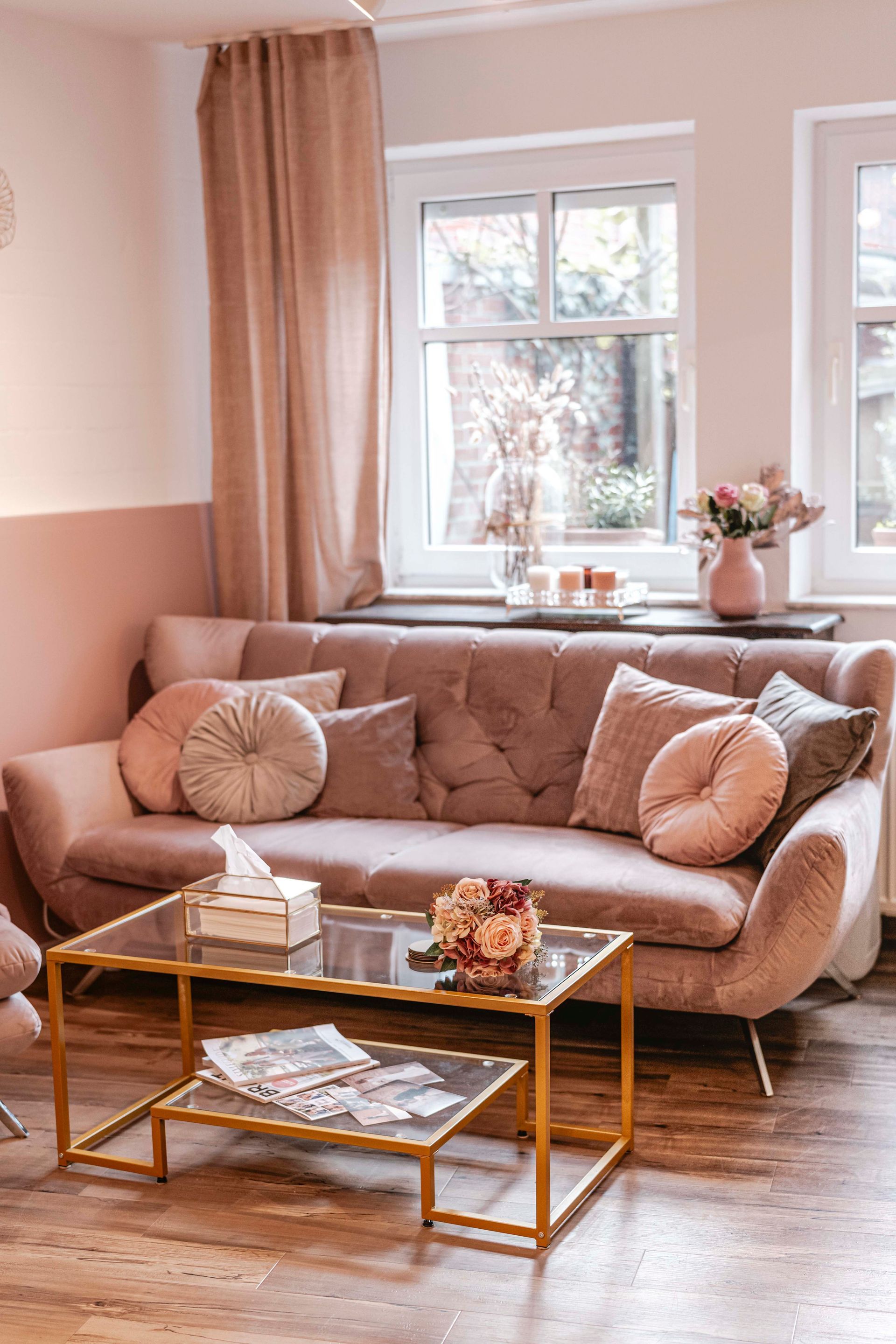 Ein Wohnzimmer mit einem rosa Sofa und einem Couchtisch aus Glas.
