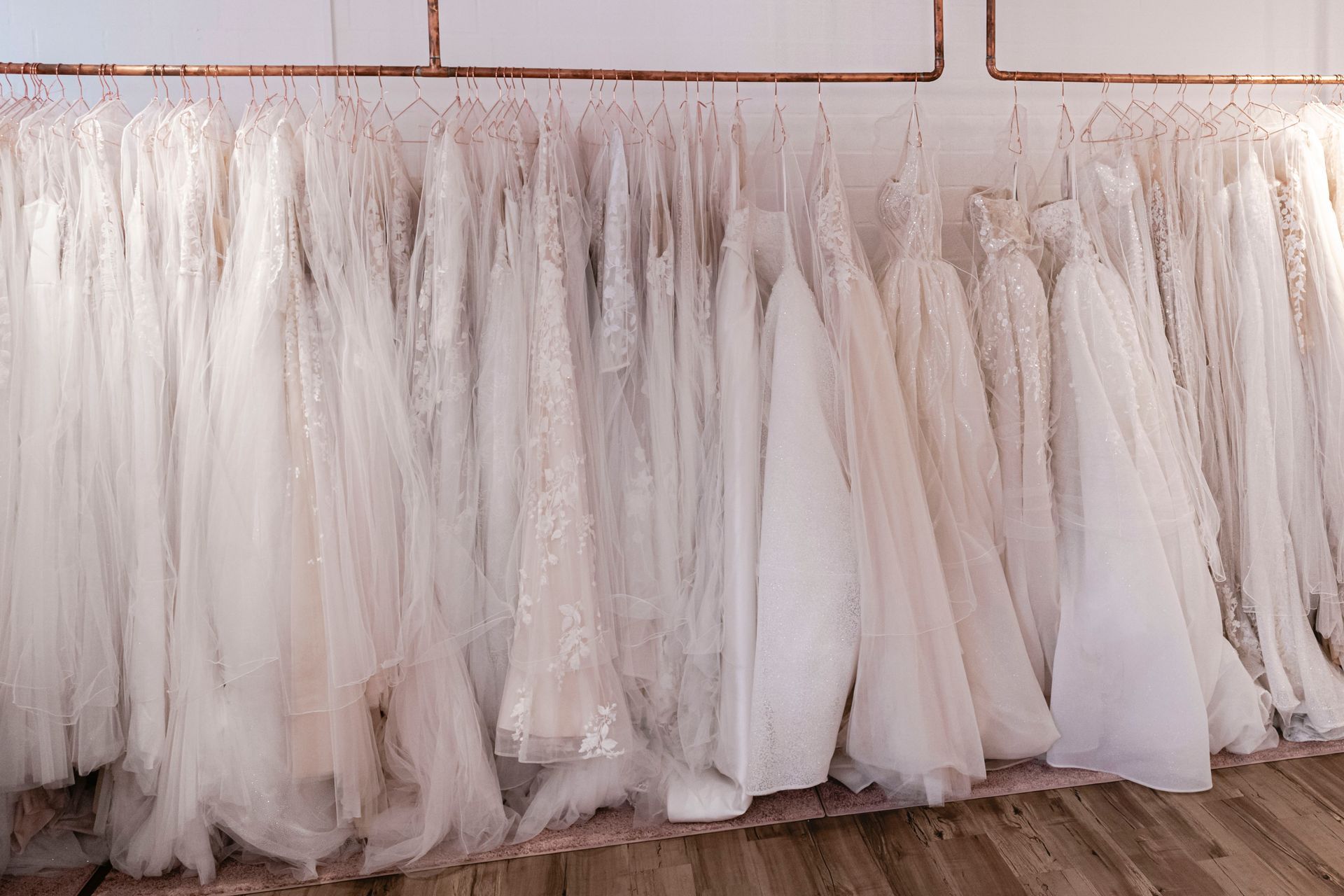 Eine Reihe von Brautkleidern hängt in einem Geschäft an einer Kleiderstange.