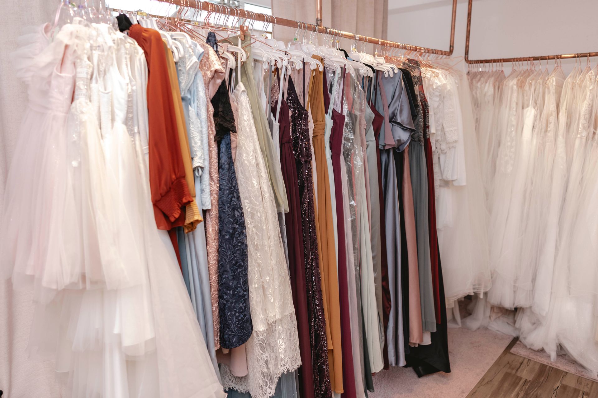 Ein Raum voller Kleider, die auf Kleiderständern hängen.
