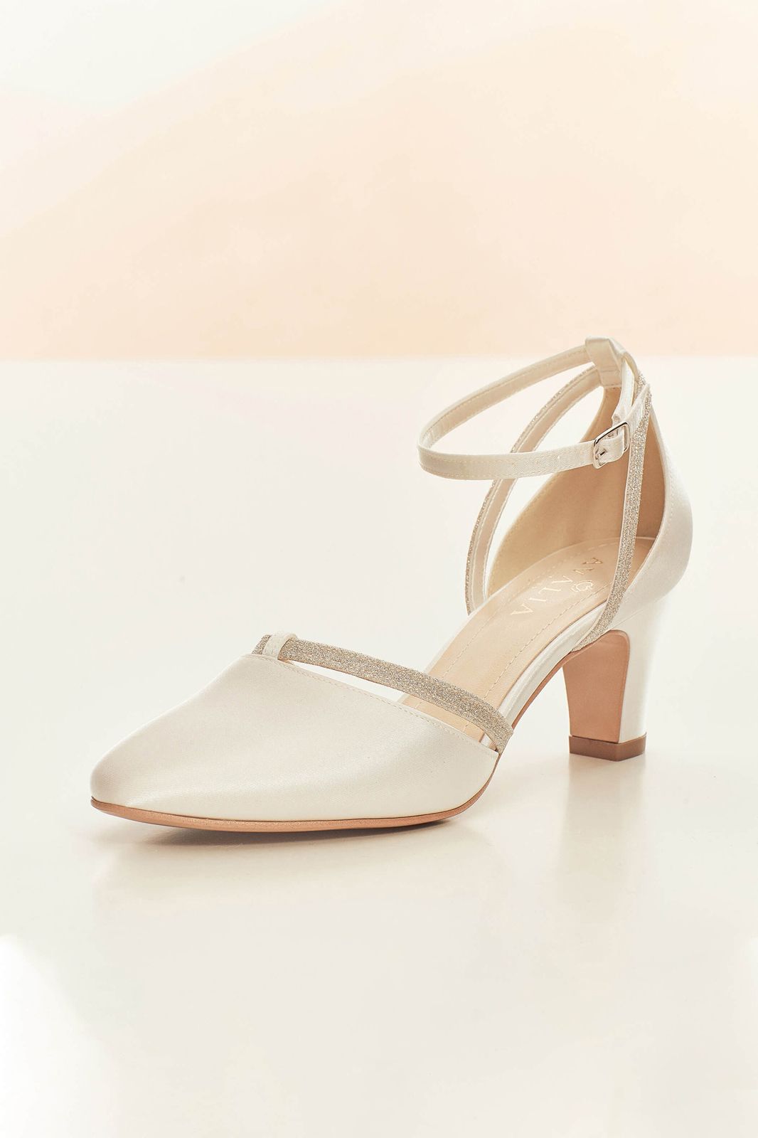 Ein Paar weiße Brautschuhe mit Fesselriemchen und Strasssteinen auf weißem Untergrund.