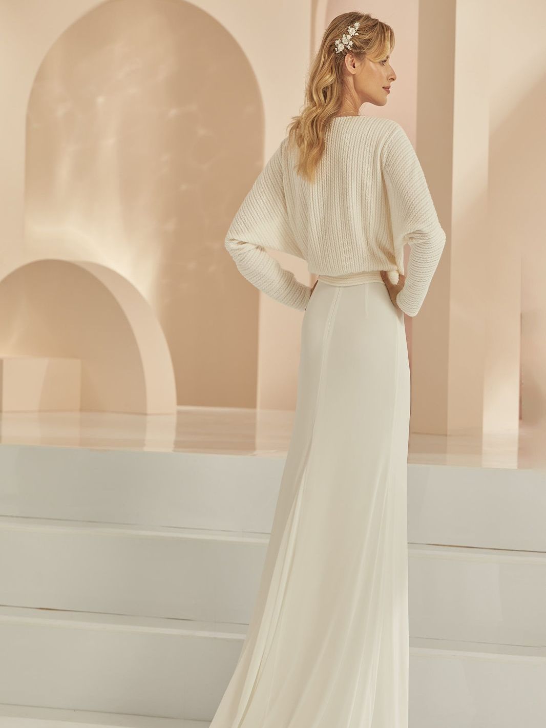 Eine Frau trägt ein weißes Brautkleid mit langer Schleppe.