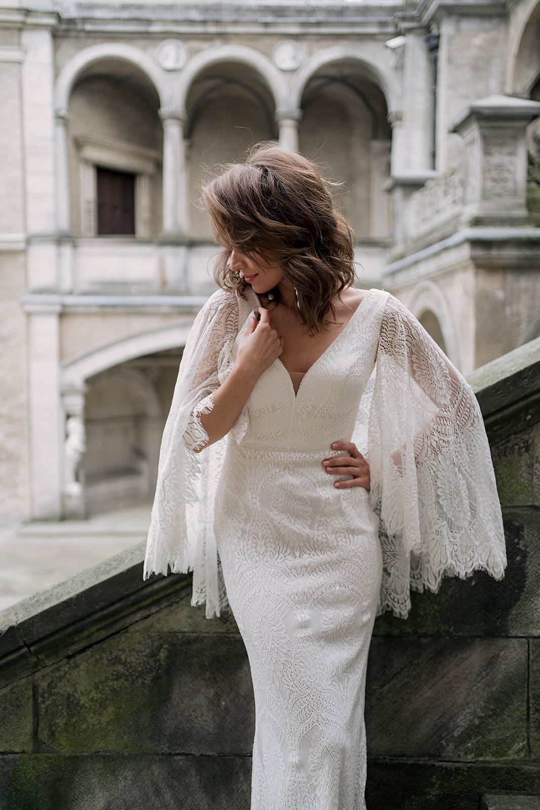 Eine Frau in einem Brautkleid steht an einem steinigen Strand.