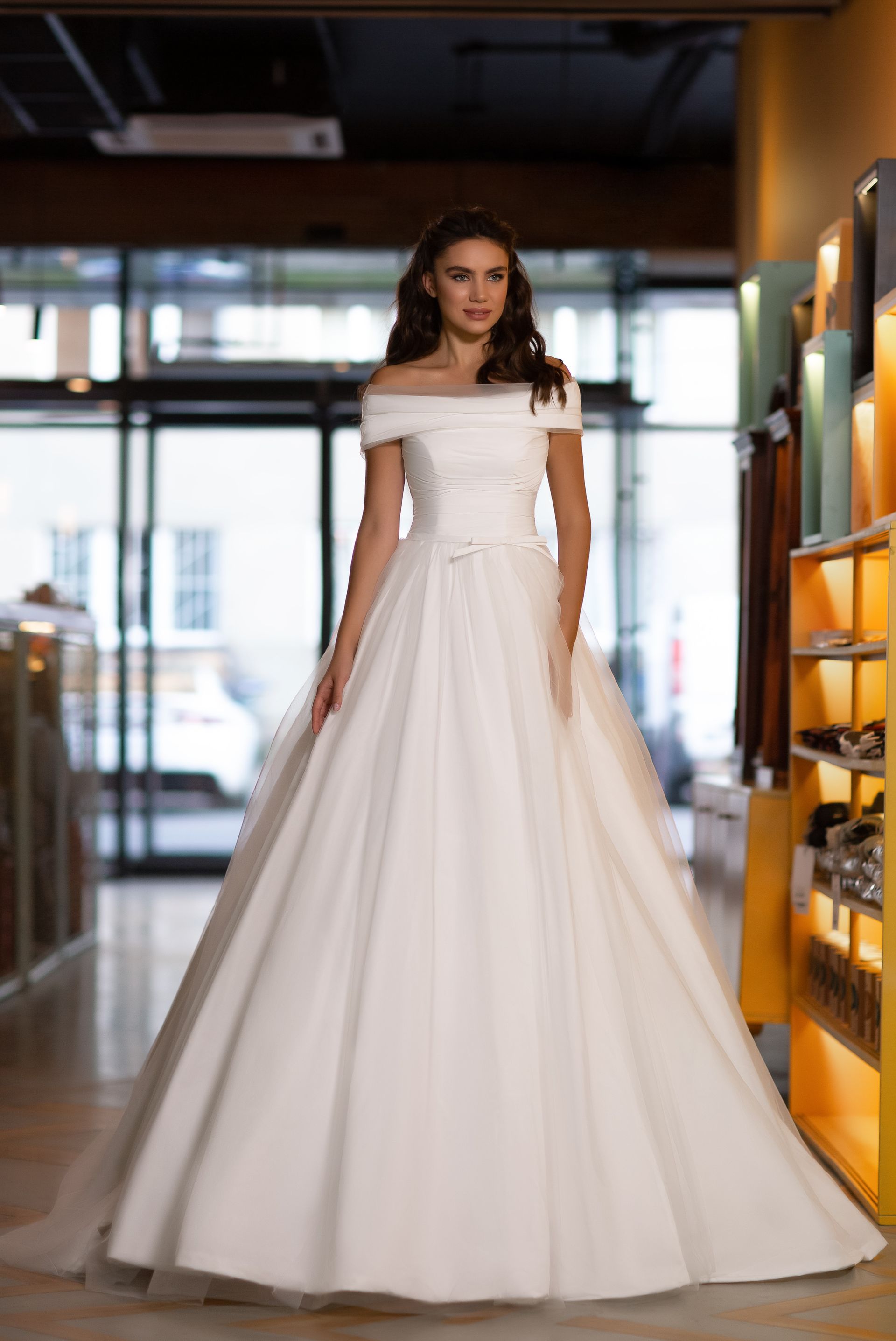 Eine Frau in einem weißen Brautkleid steht vor lila Blumen.