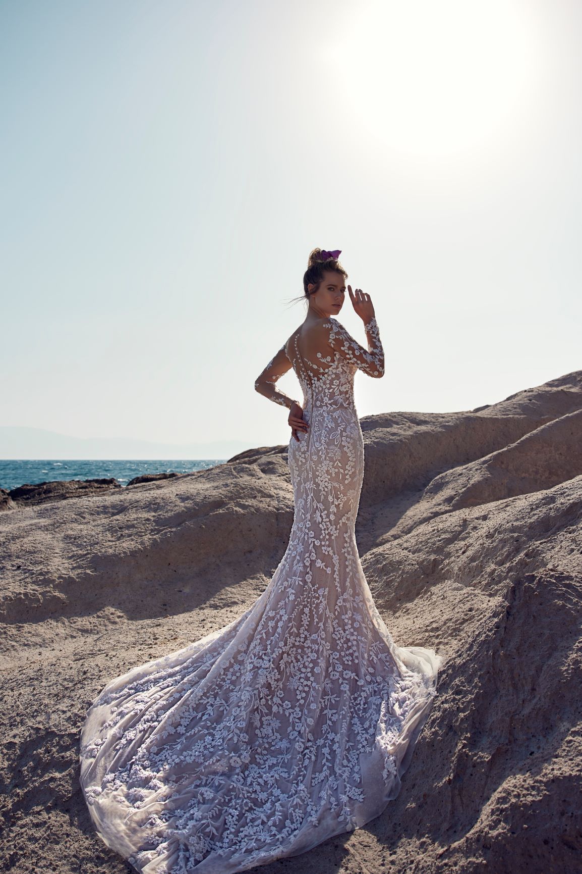 Eine Frau in einem Brautkleid steht an einem steinigen Strand.