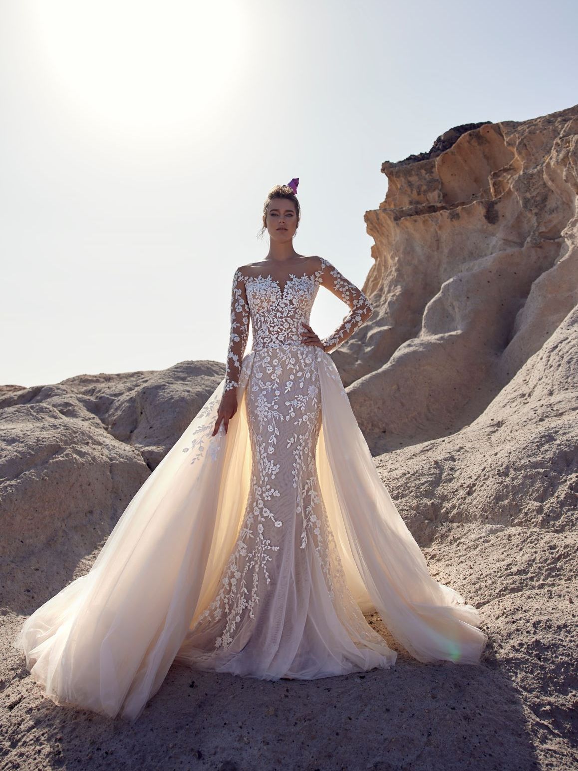 Eine Frau in einem Brautkleid steht in der Wüste.