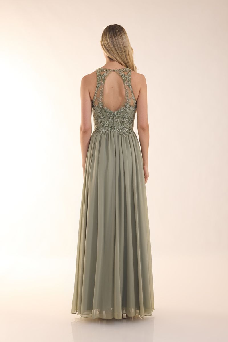 Eine Frau in einem grünen Kleid steht vor einer Holztür.