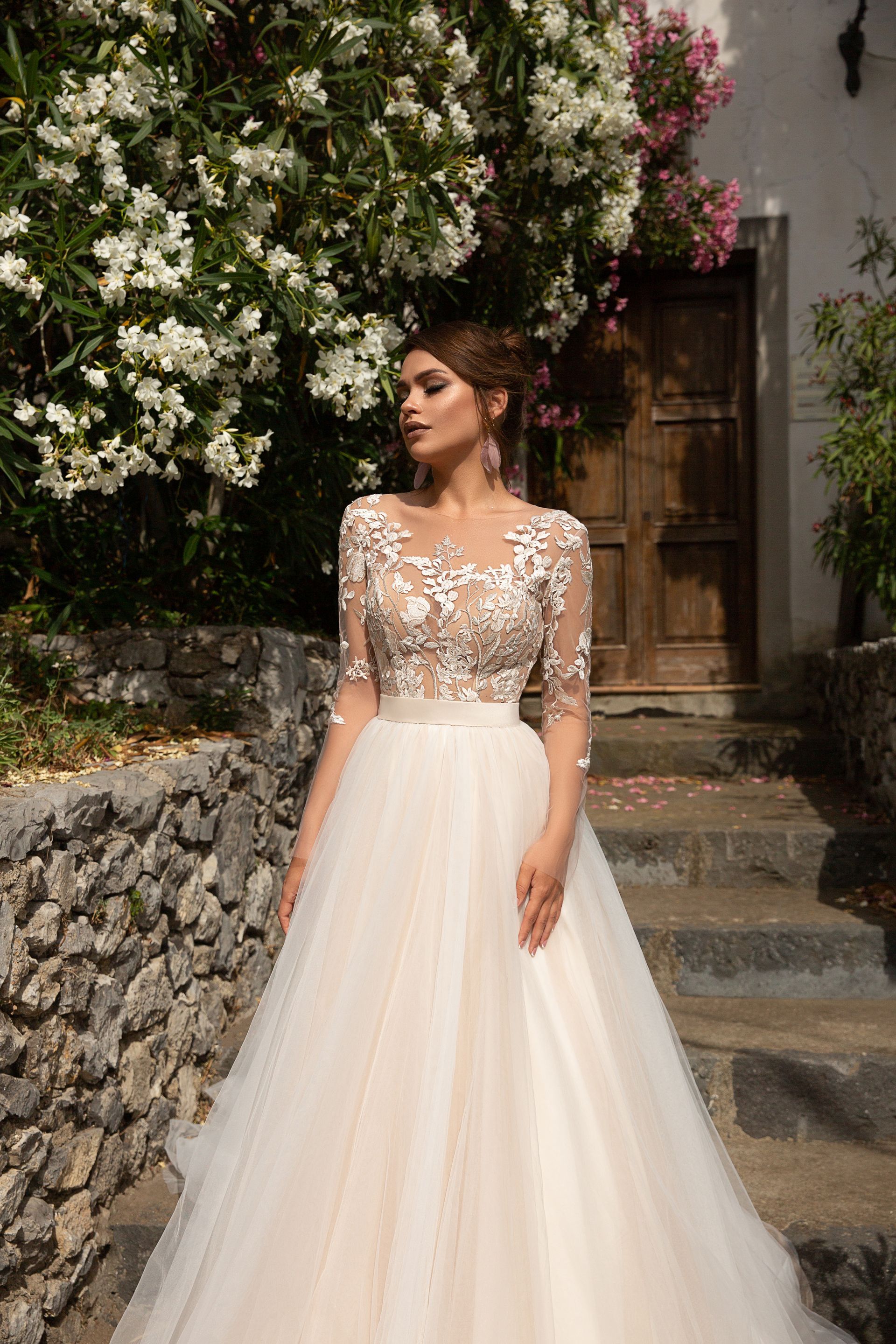 Eine Frau in einem weißen Kleid steht vor Blumen.