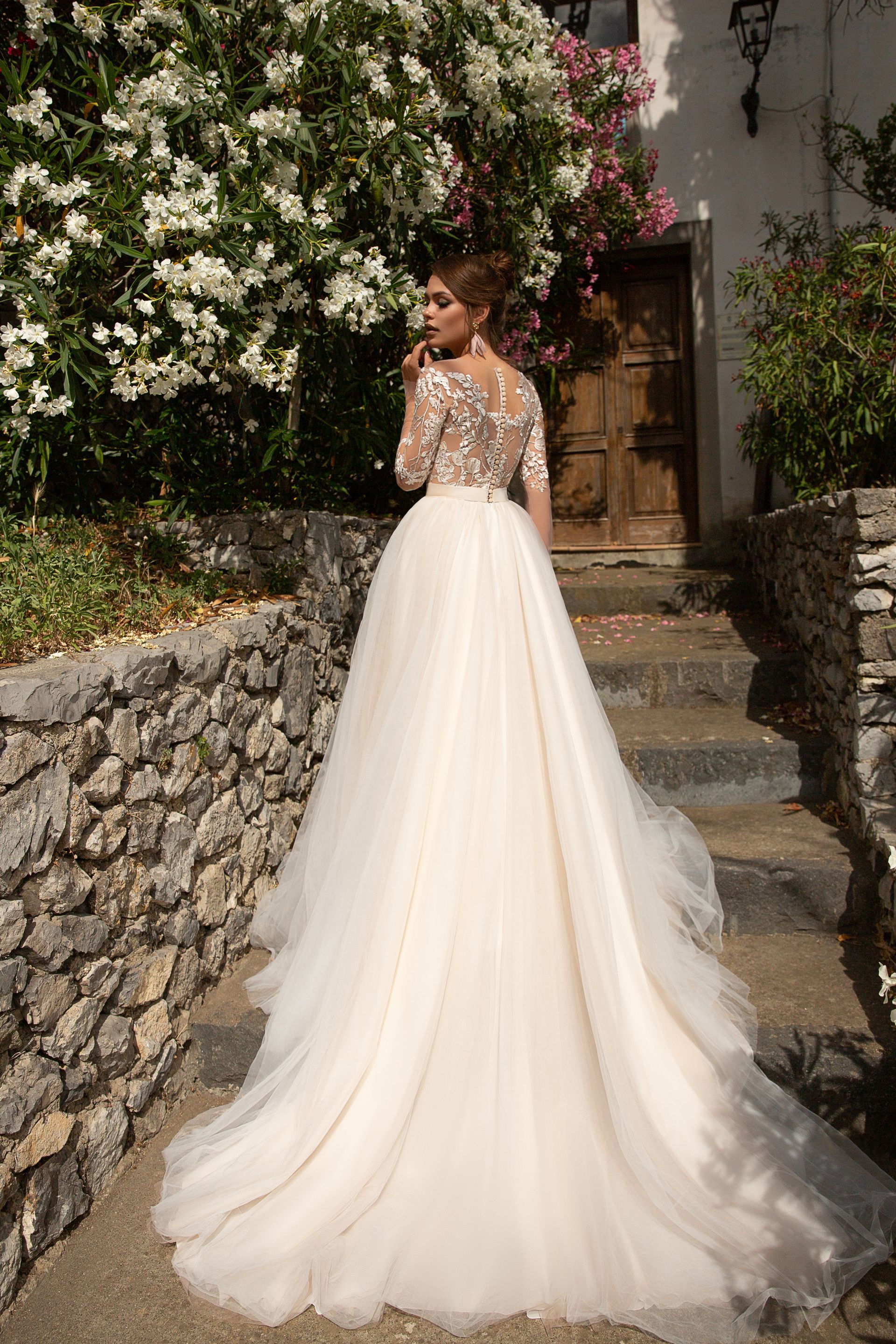 Eine Frau in einem Brautkleid steht auf einer Treppe vor einem Gebäude.