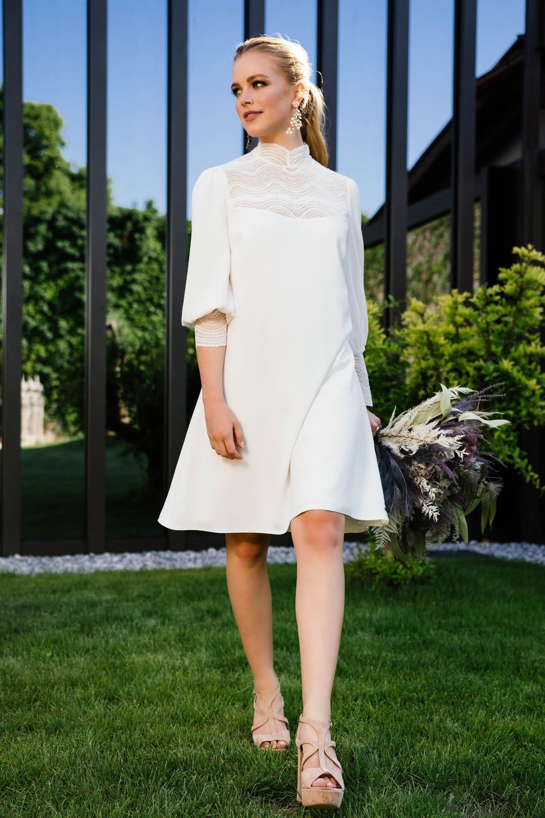 Eine Frau in einem weißen Kleid steht im Gras.