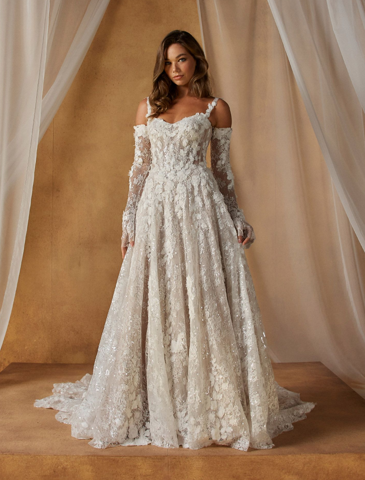 Eine Frau in einem Brautkleid steht vor einer Blumenwand.