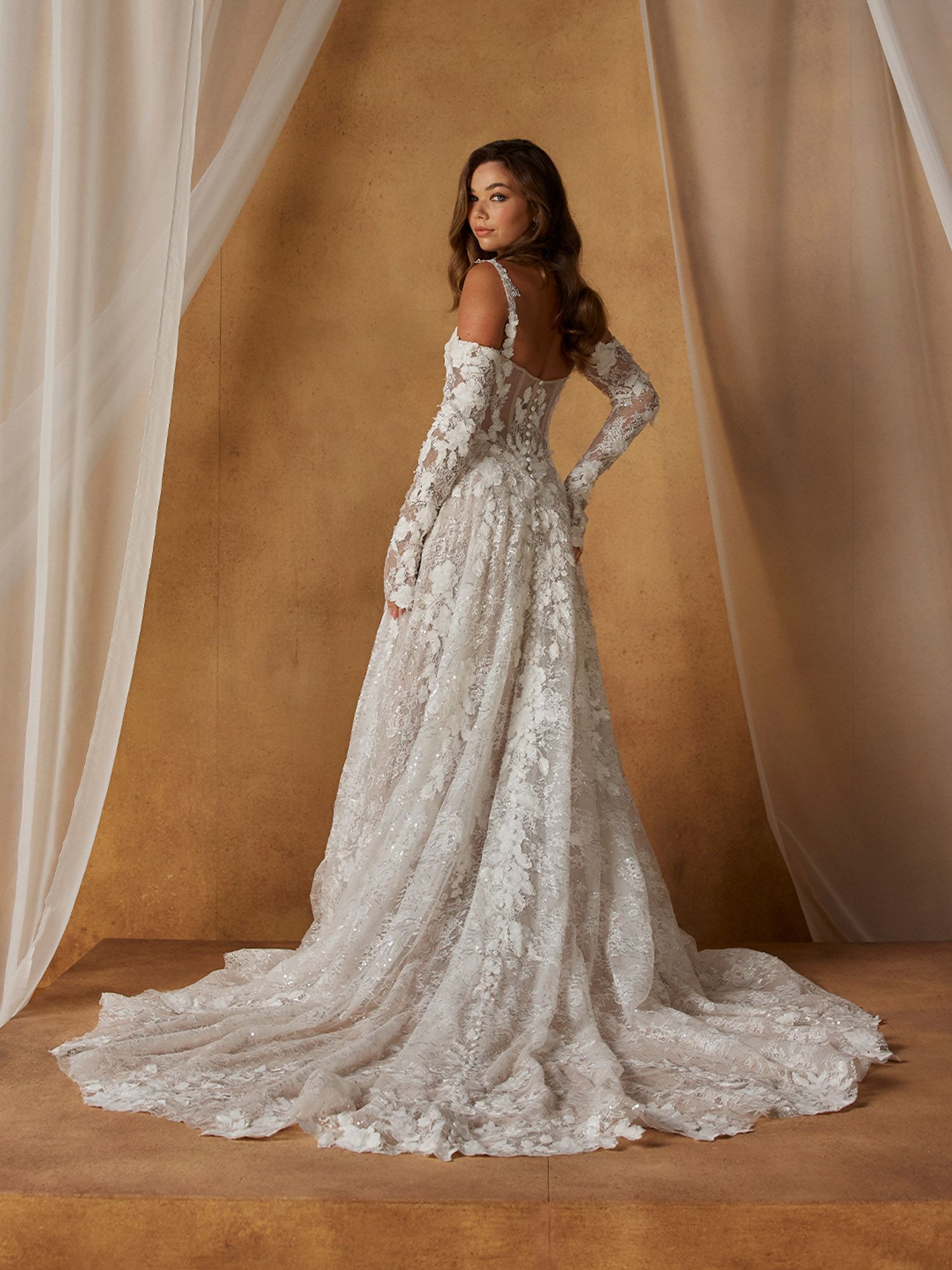 Eine Frau in einem Brautkleid steht vor einer Blumenwand.