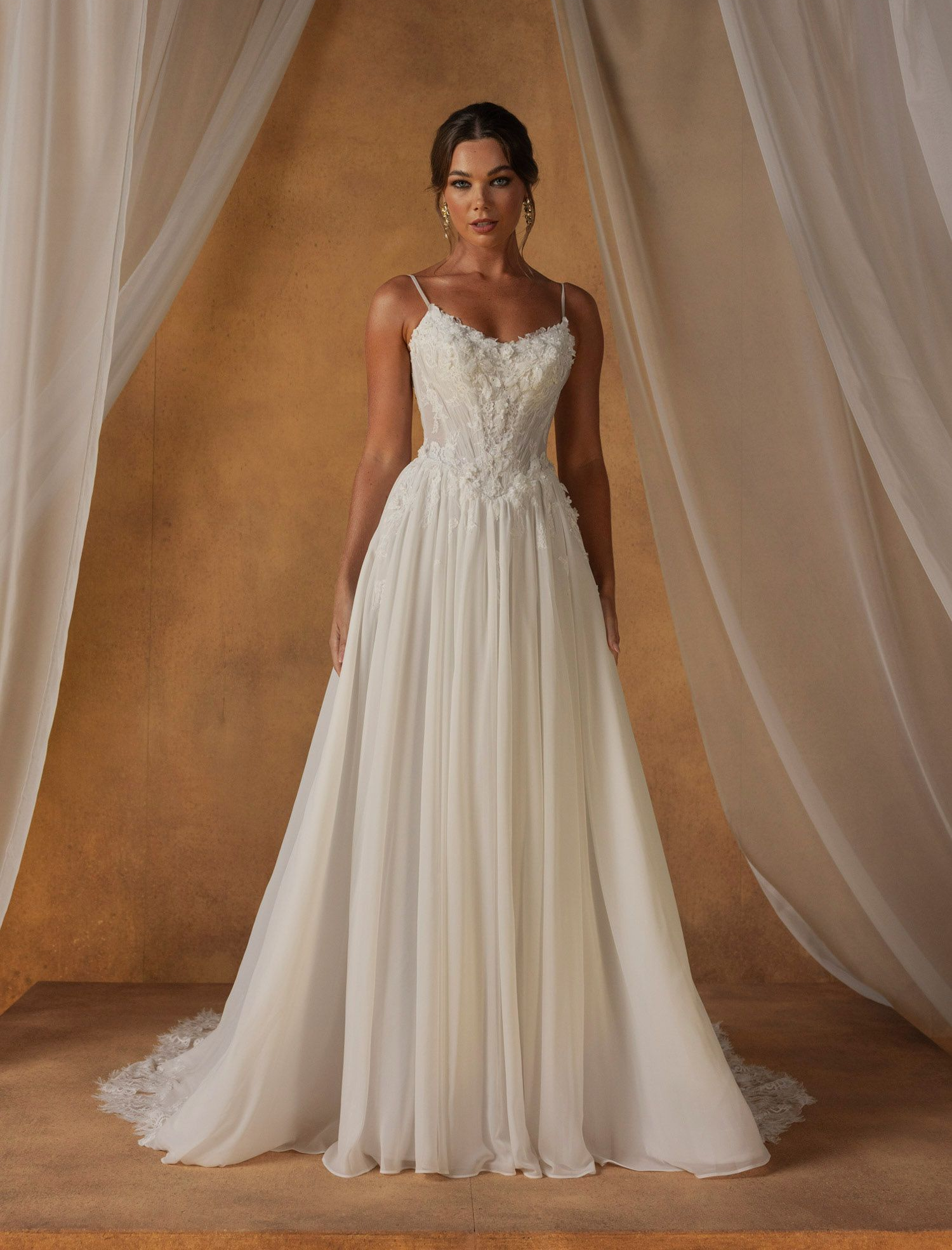 Eine Frau in einem Brautkleid steht vor einer Wand aus rosa Blumen.