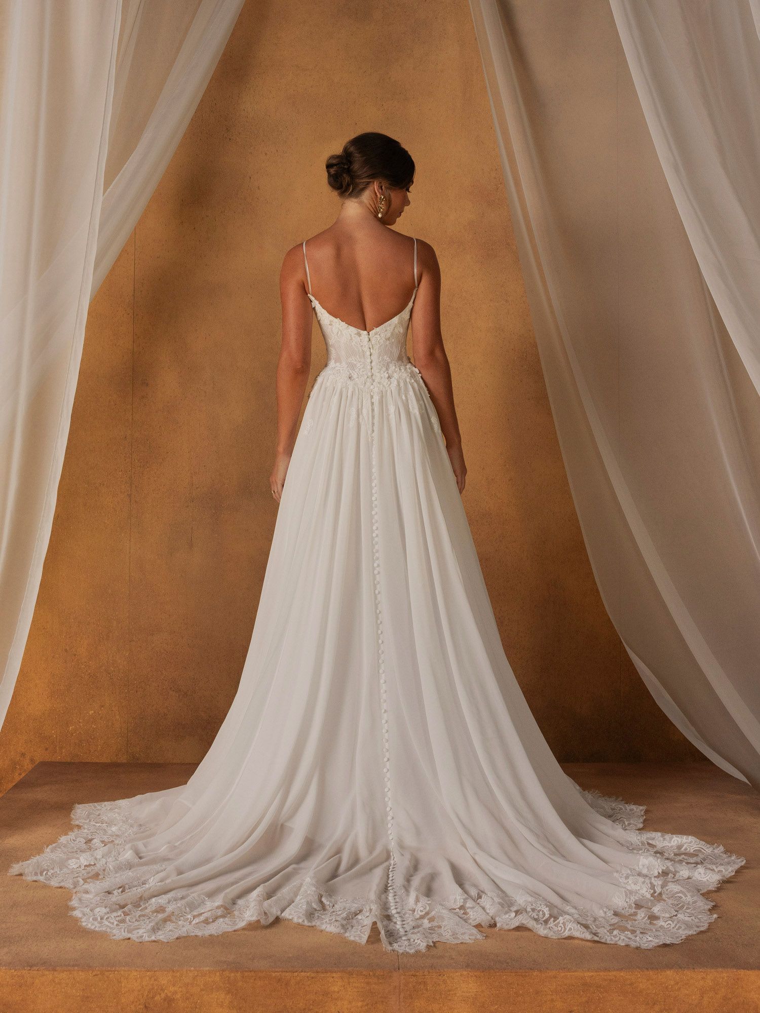 Eine Frau in einem Brautkleid steht vor einer Blumenwand.