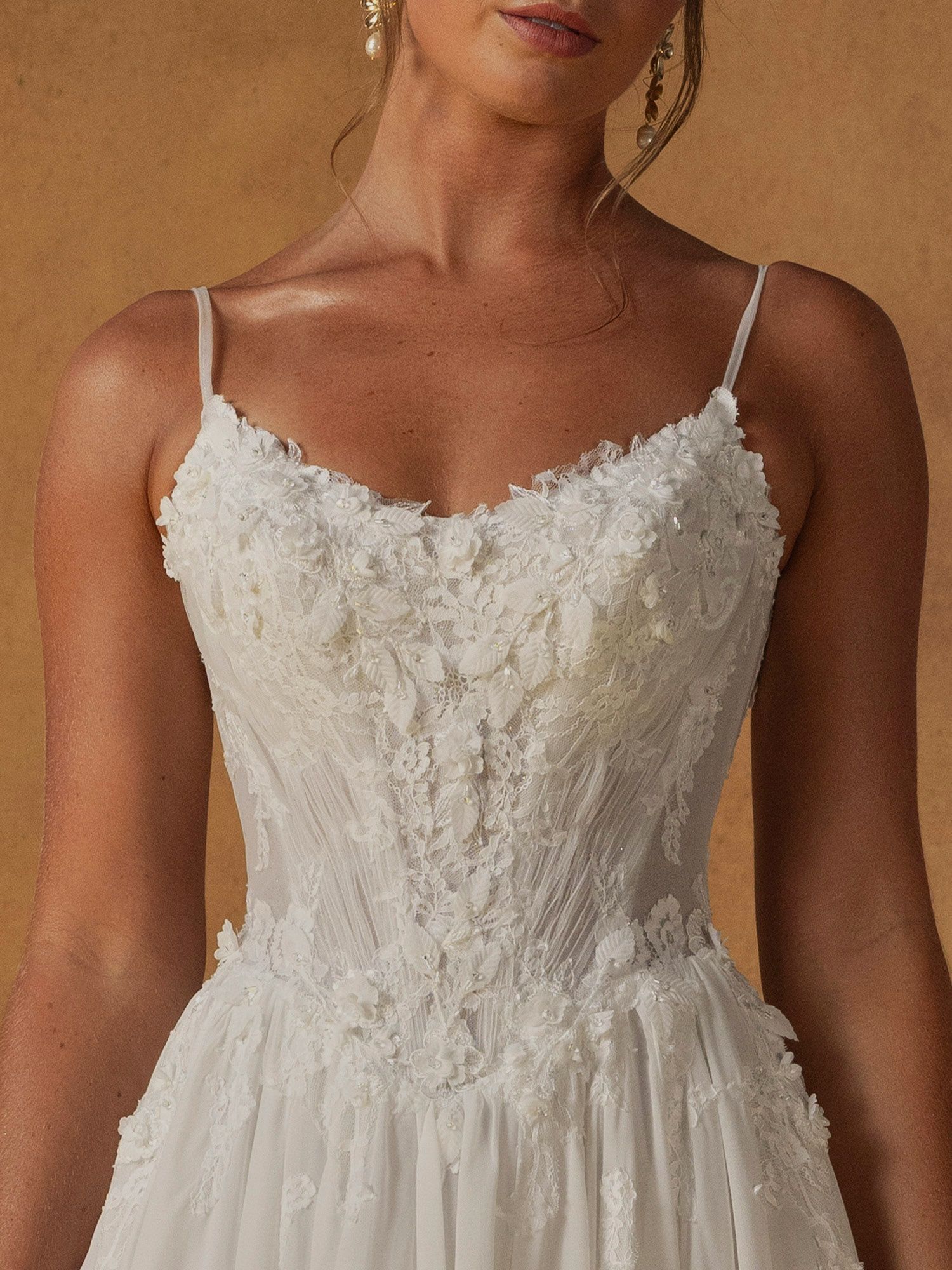 Eine Frau in einem weißen Brautkleid steht vor Blumen.