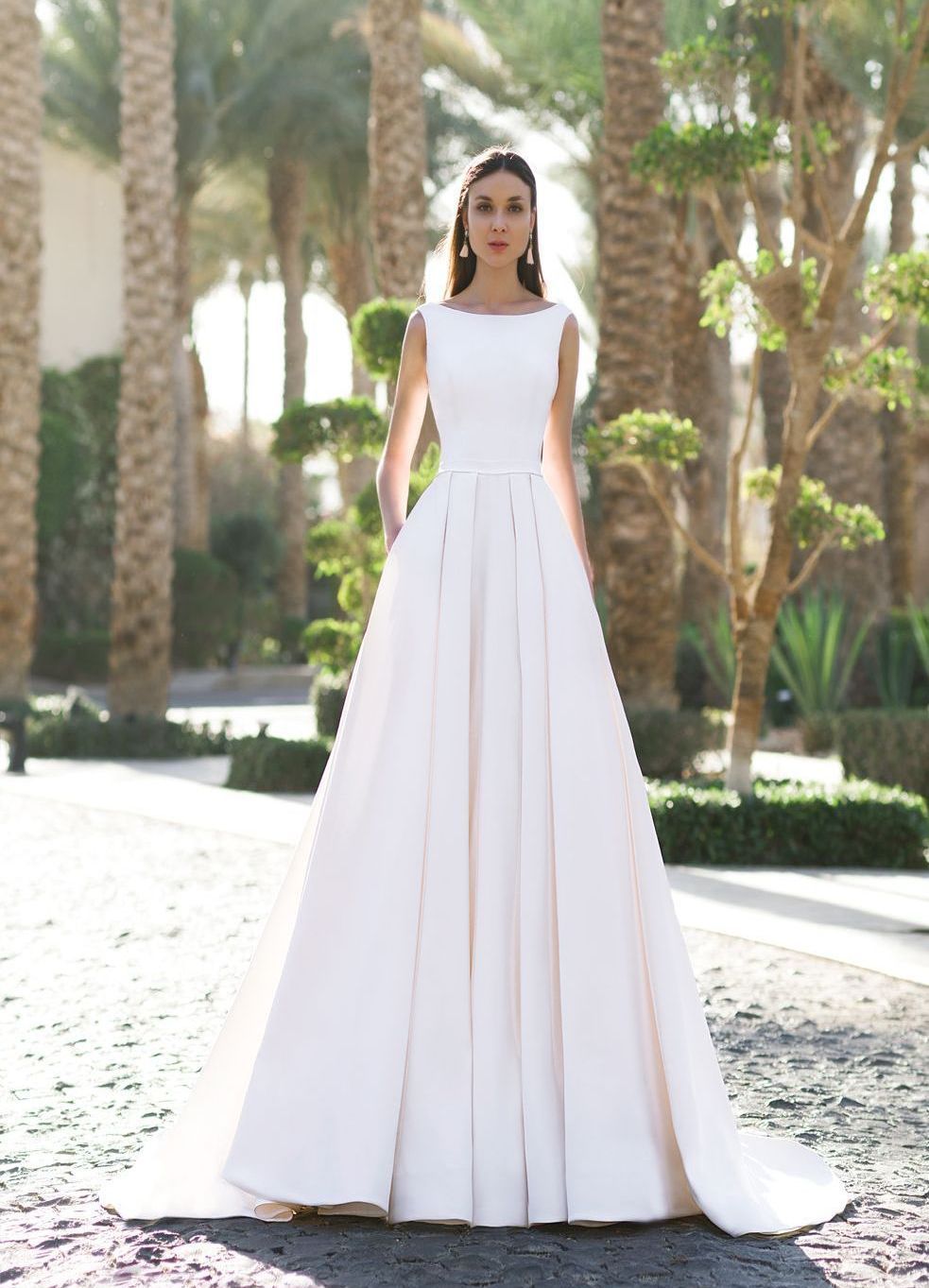 Eine Frau in einem weißen Brautkleid steht vor lila Blumen.
