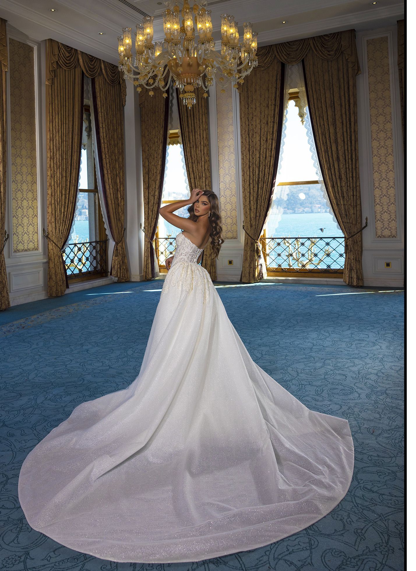 Eine Frau in einem Brautkleid steht in einem Raum mit einem Kronleuchter.