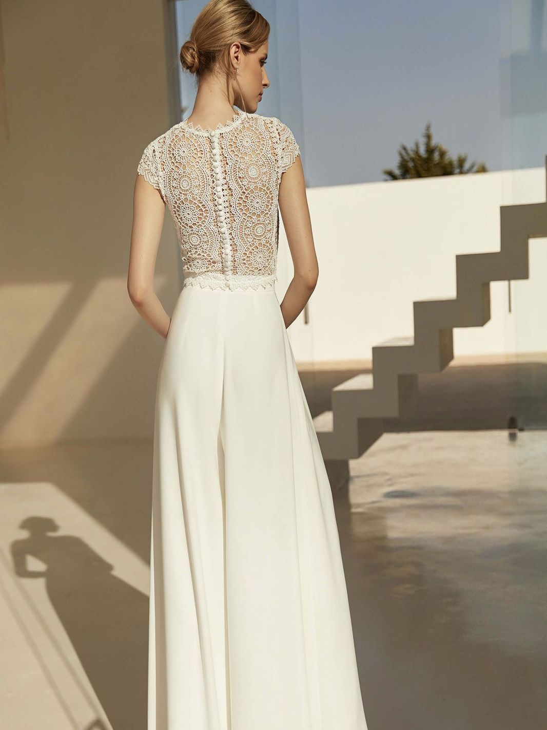 Eine Frau in einem weißen Kleid steht vor einer Treppe