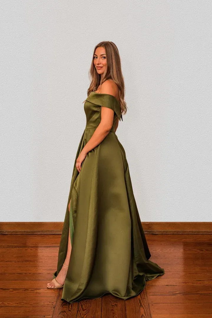 Eine Frau in einem grünen Kleid steht auf einem Holzboden.