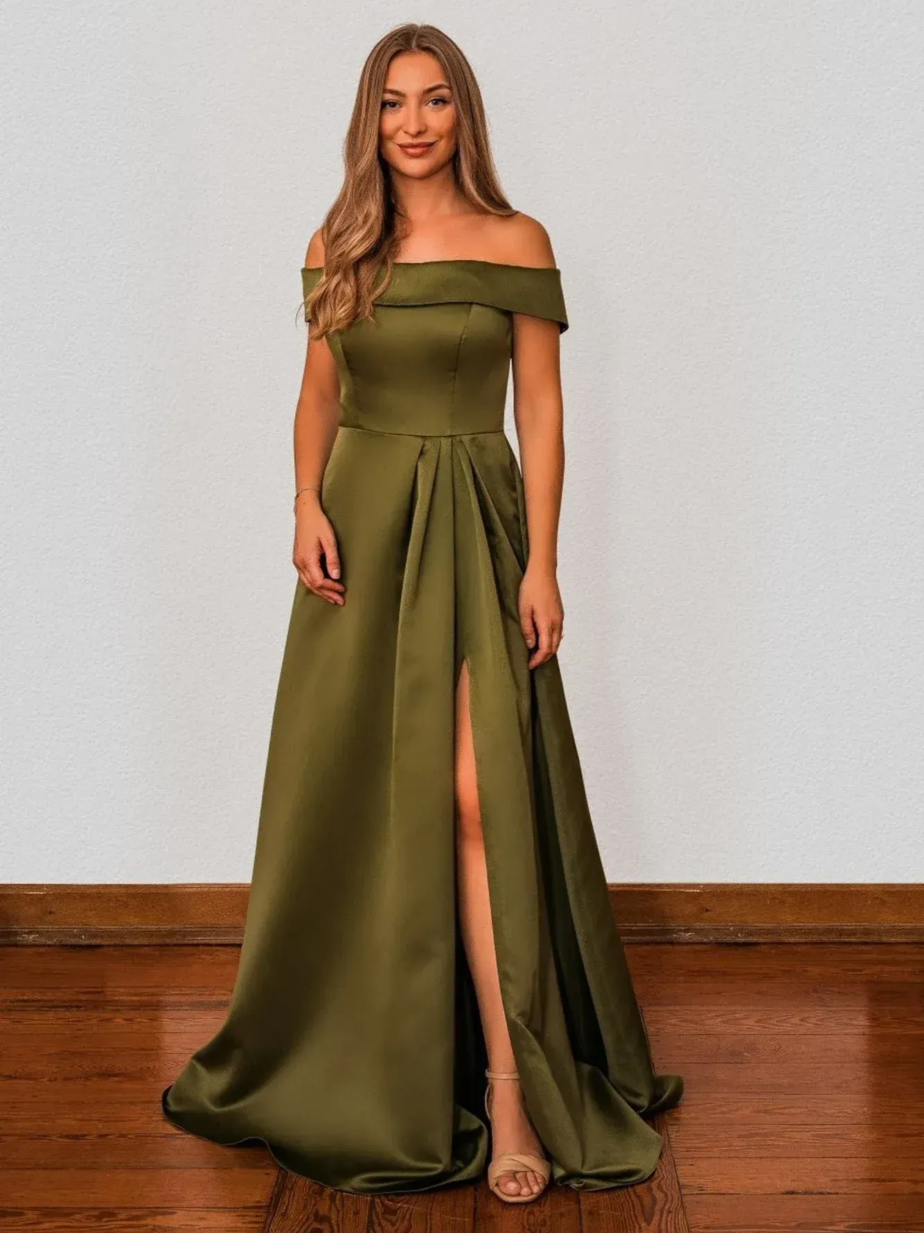 Eine Frau in einem grünen schulterfreien Kleid steht auf einem Holzboden.