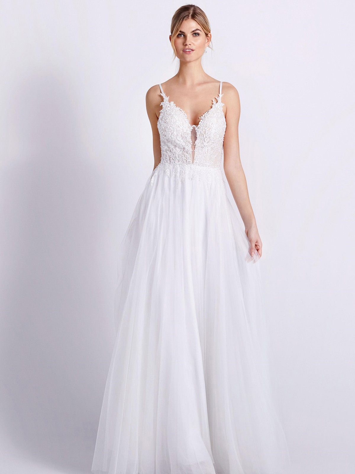 Eine Frau in einem Brautkleid steht vor einer Blumenwand.