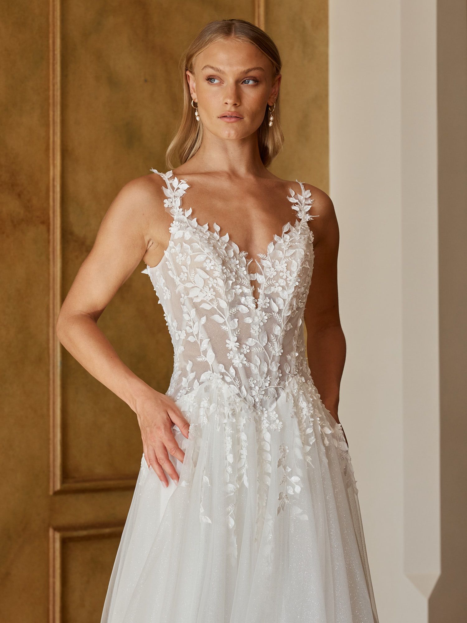 Eine Frau in einem Brautkleid steht an einem steinigen Strand.