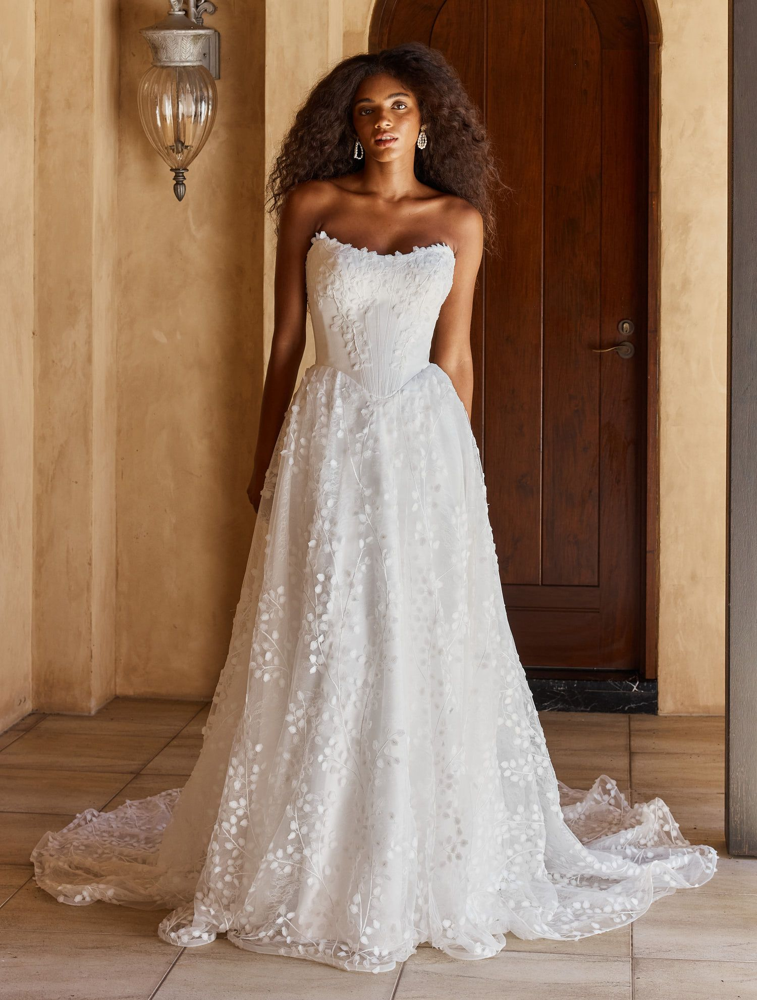 Eine Frau in einem Brautkleid steht vor einer Blumenwand.