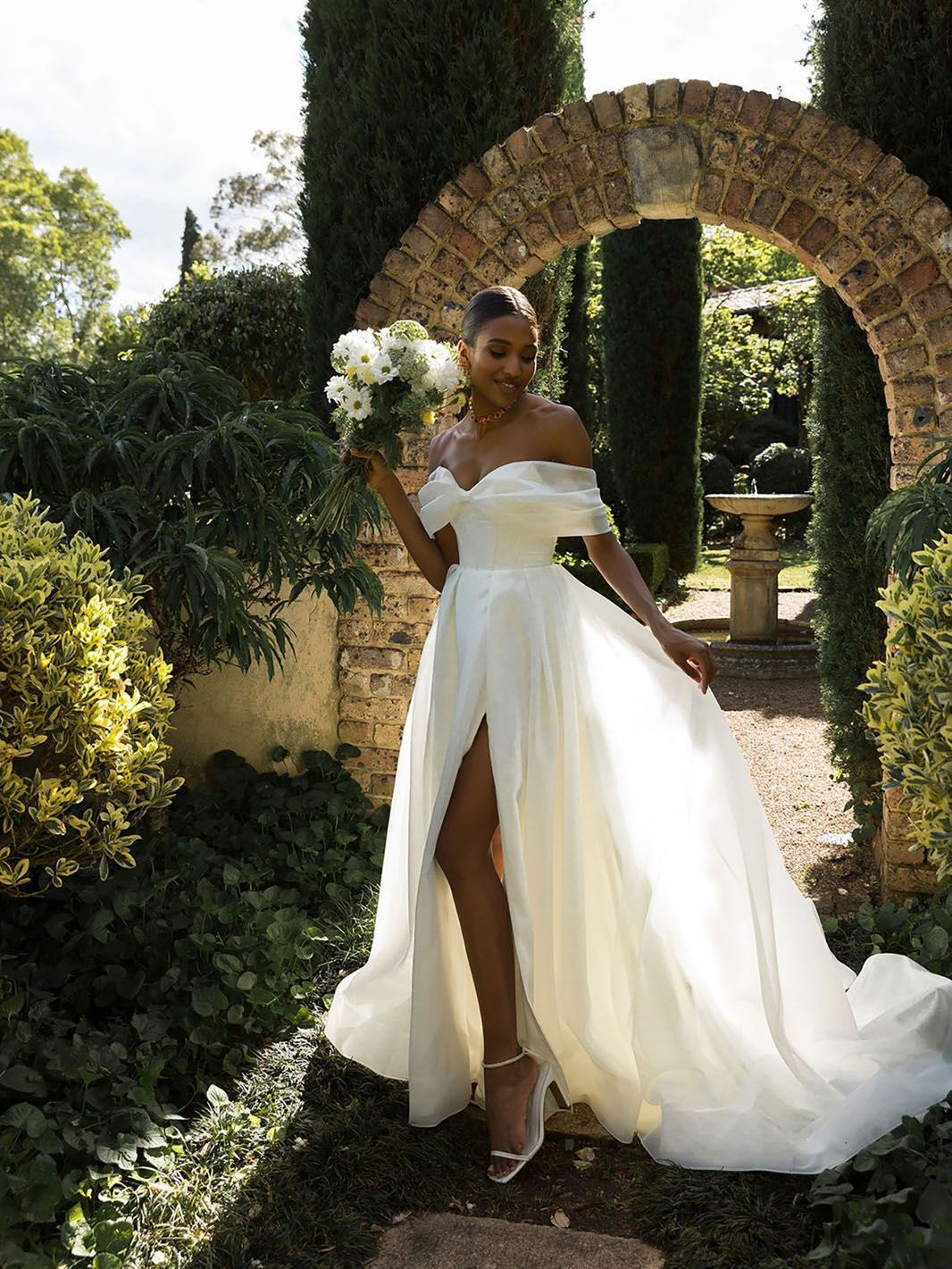 Eine Frau in einem weißen Brautkleid hält einen Blumenstrauß.
