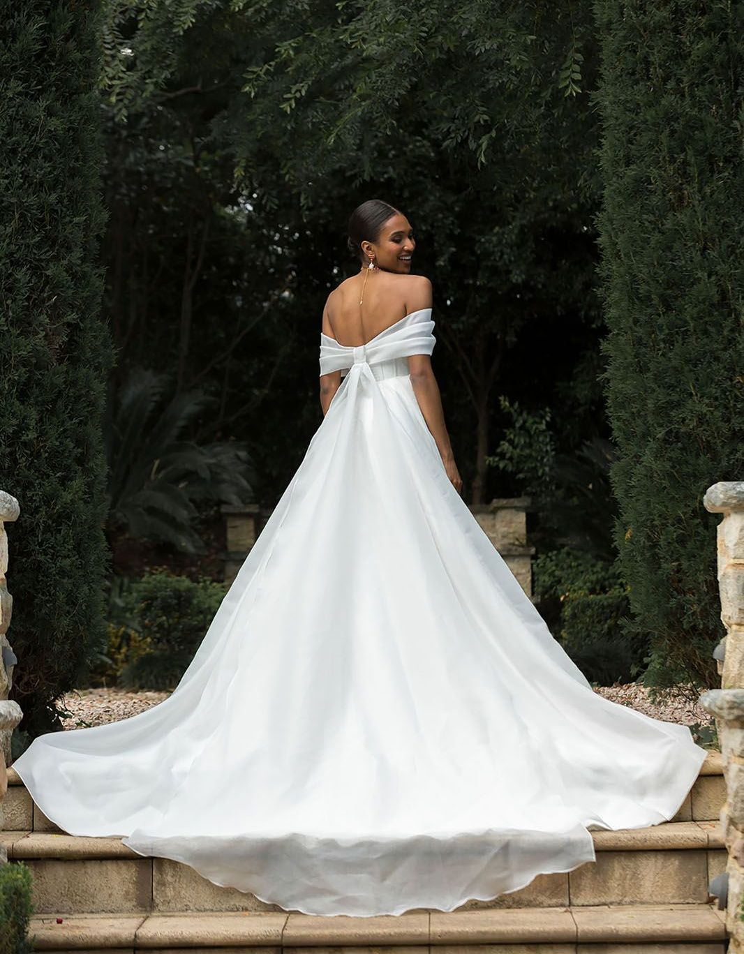 Eine Frau in einem weißen Brautkleid steht auf einer Treppe.