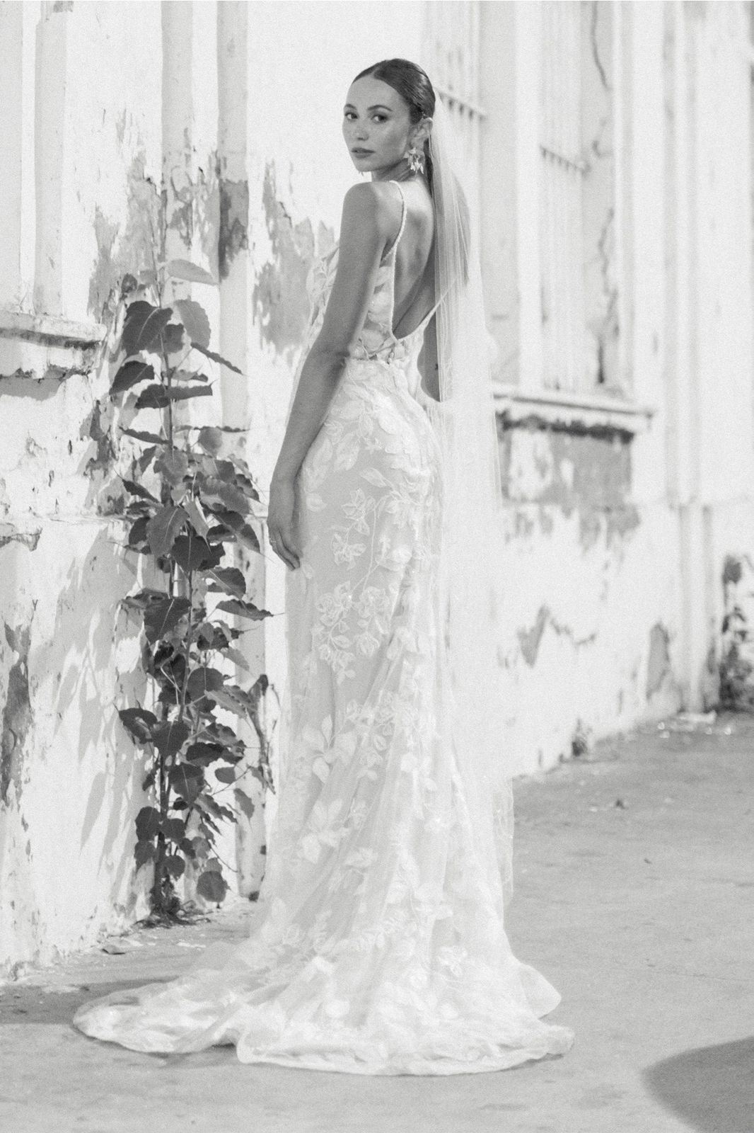 Eine Frau trägt ein weißes Kleid mit einer Schulter und langen Ärmeln.