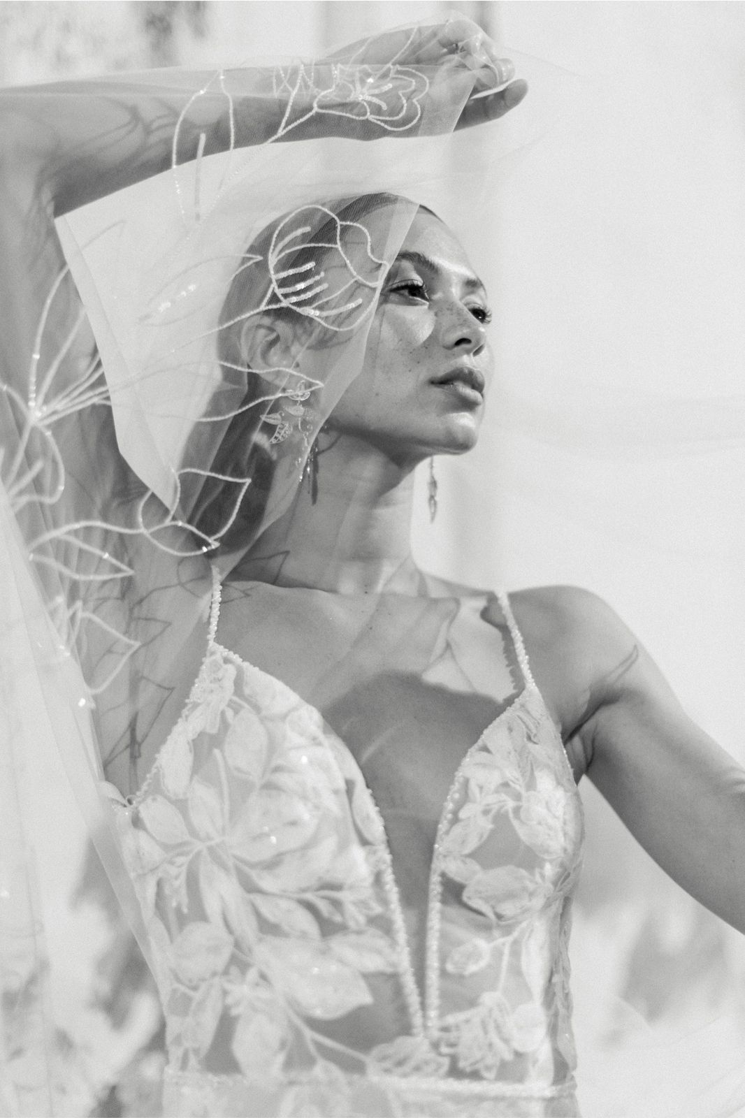 Eine Frau trägt ein weißes Brautkleid mit langen Ärmeln und einem Pferdeschwanz.