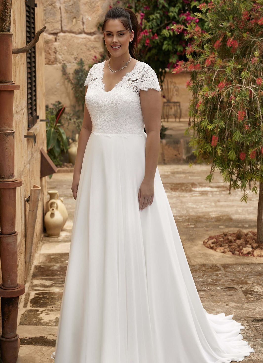 Eine Frau in einem weißen Brautkleid steht vor einem Gebäude.
