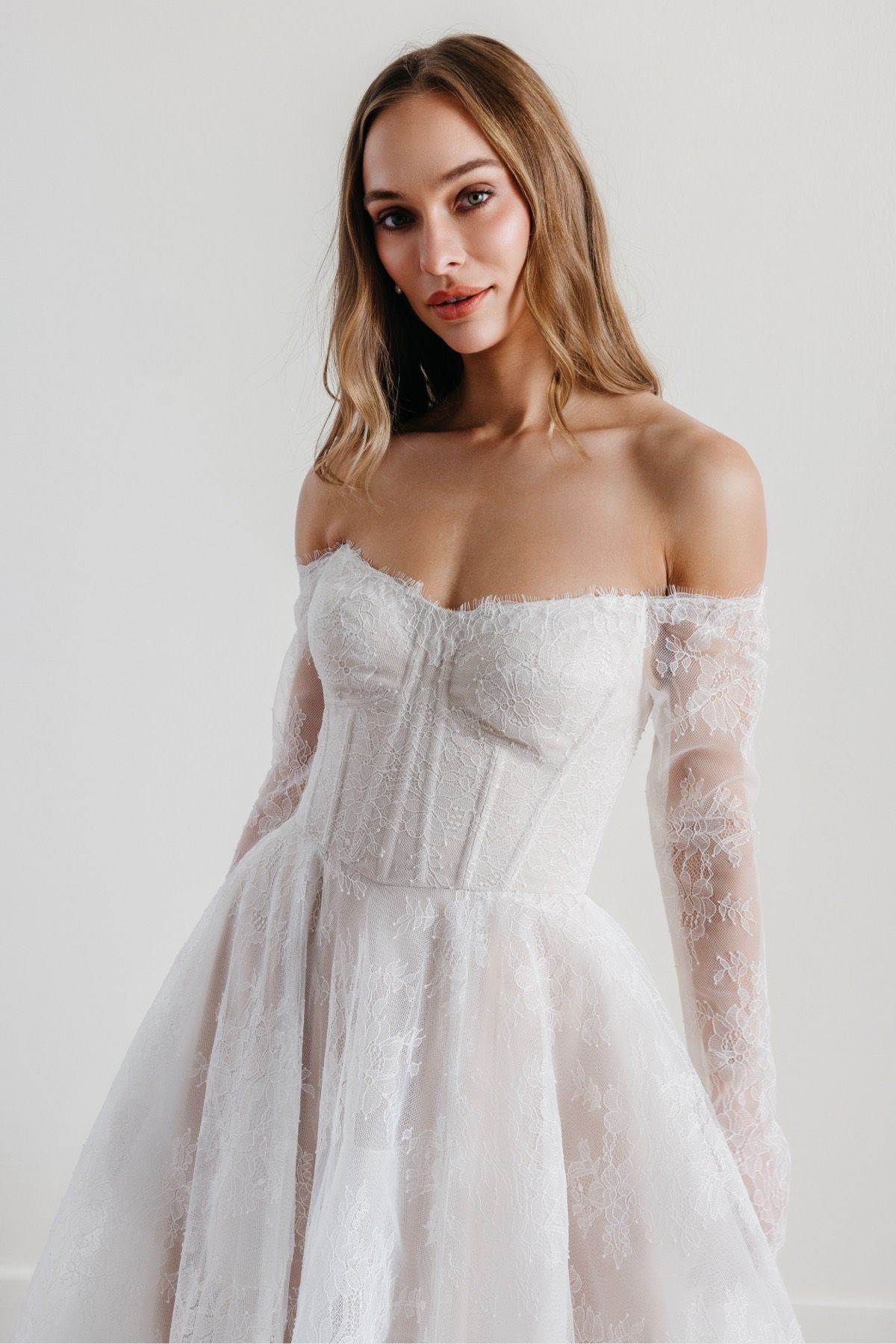 Eine Frau in einem Brautkleid steht an einem steinigen Strand.