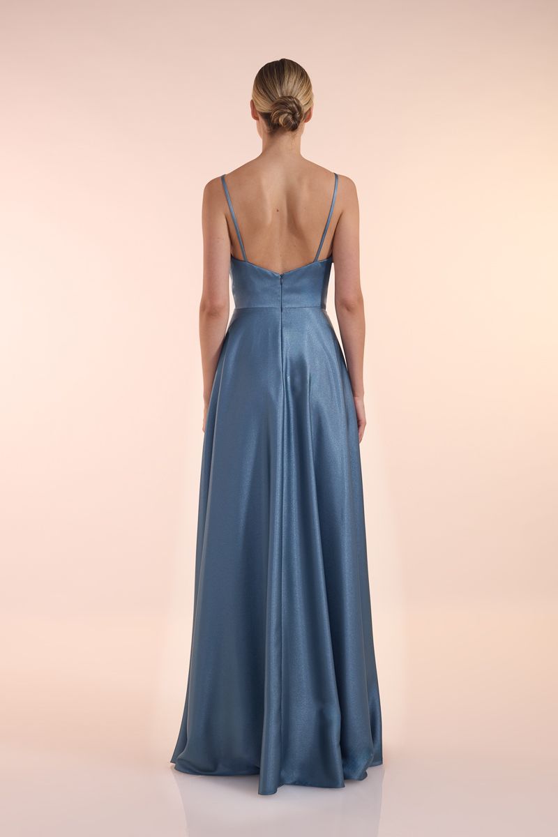 Eine Frau in einem grünen Kleid steht vor einer Holztür.