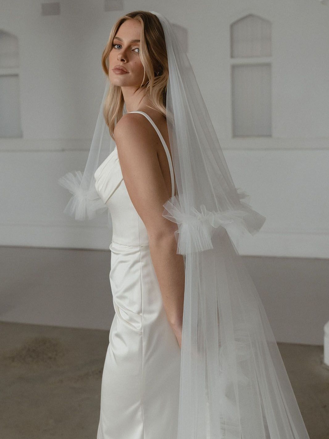 Eine Frau in einem Brautkleid und Schleier steht in einem Raum.