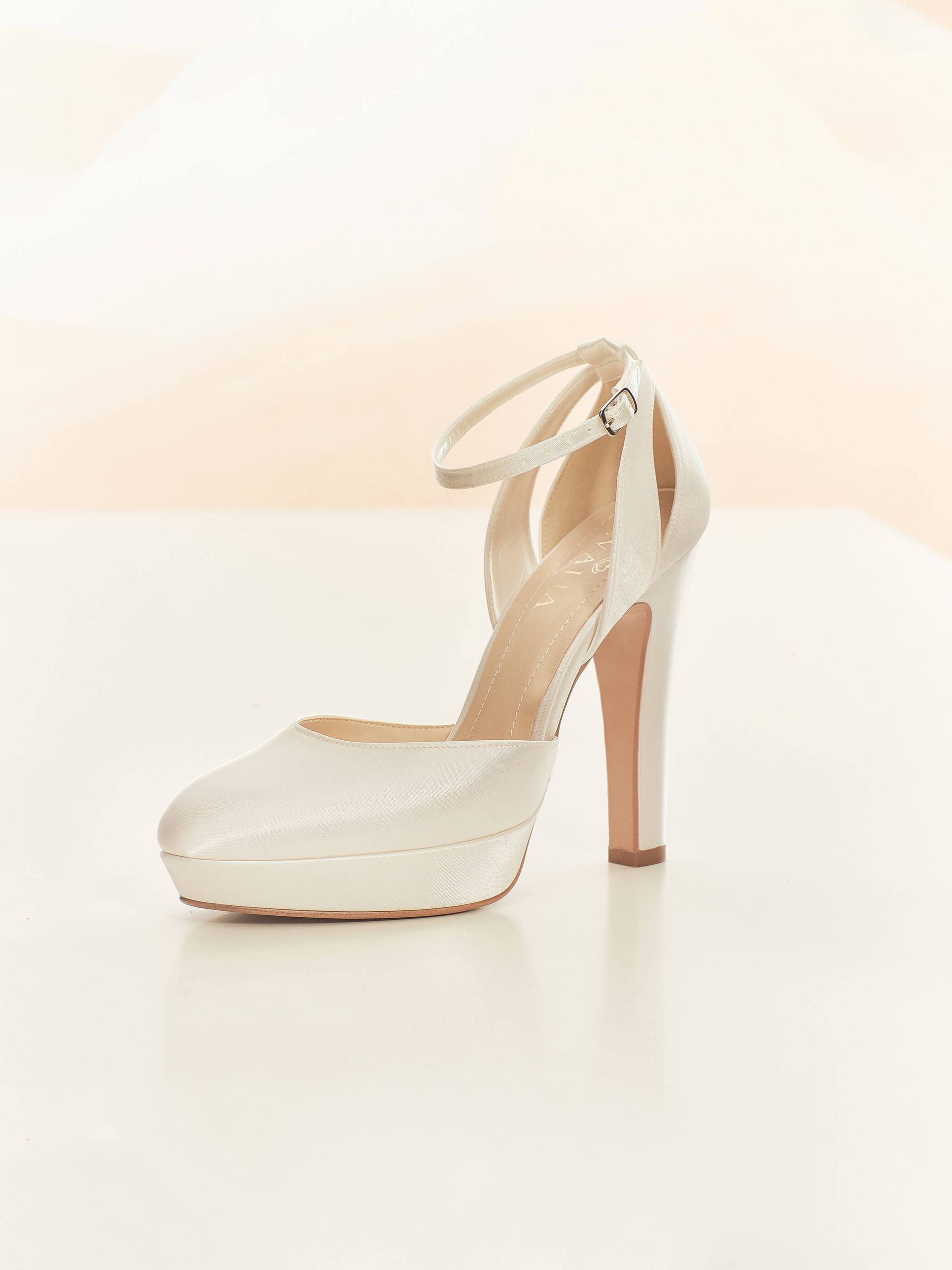 Ein Paar weiße High Heels mit Fesselriemchen auf weißem Untergrund.