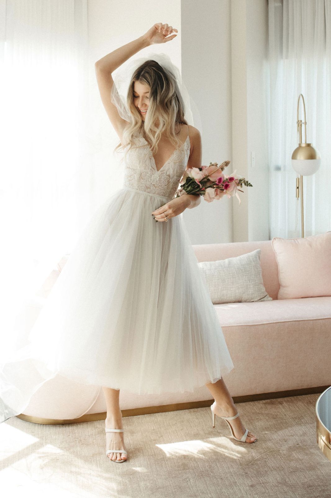 Eine Frau in einem weißen Brautkleid steht vor lila Blumen.