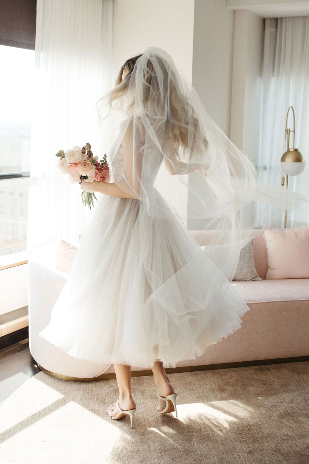 Eine Frau in einem Brautkleid steht auf einer Treppe vor einem Gebäude.