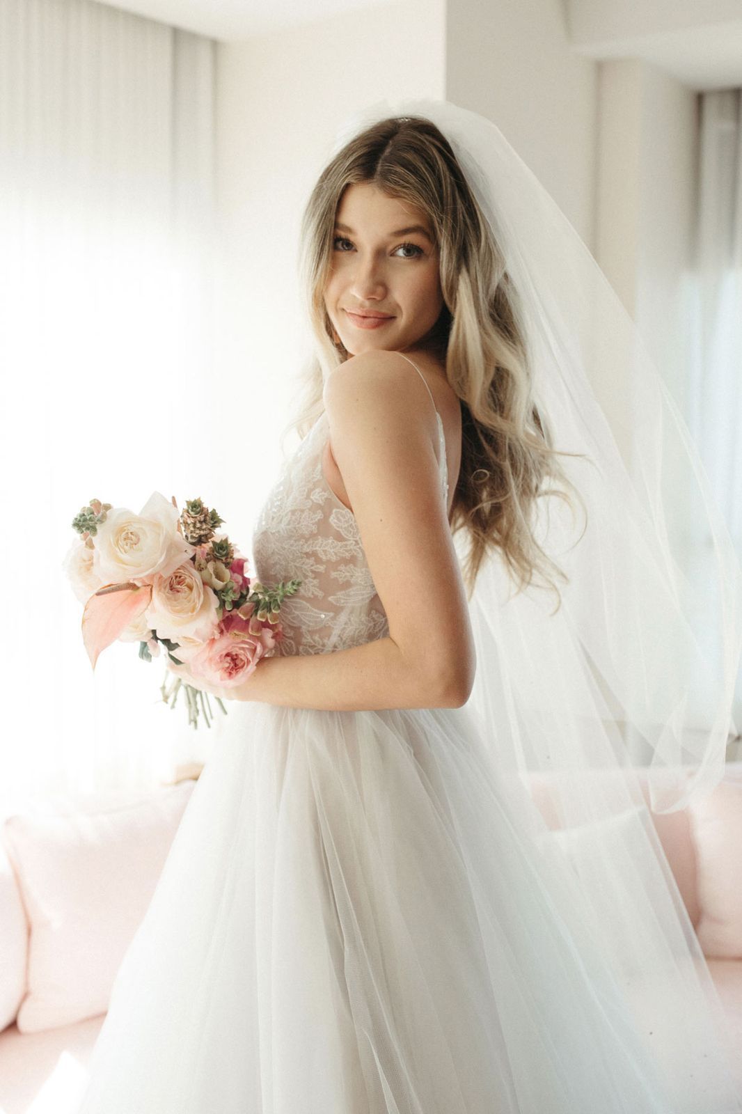 Eine Frau in einem weißen Kleid steht vor Blumen.